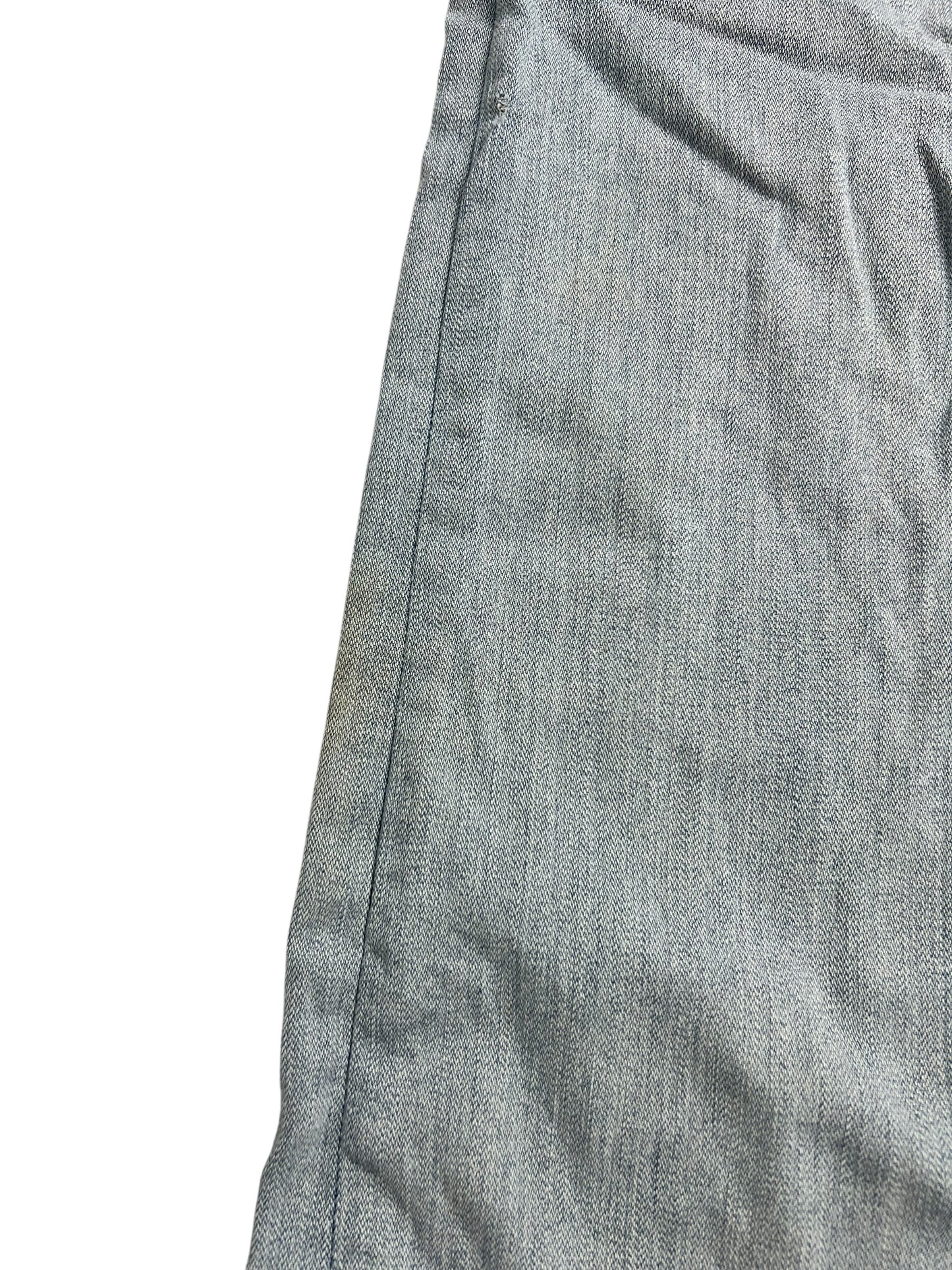 Eine Nahaufnahme des True Religion Billy Super T – Low Rise Straight (W26 x L28) von ZAZA Resell zeigt hellblauen Denim-Stoff mit einer sichtbaren Naht auf der linken Seite, leichten Falten und Flecken vor einem weißen Hintergrund.