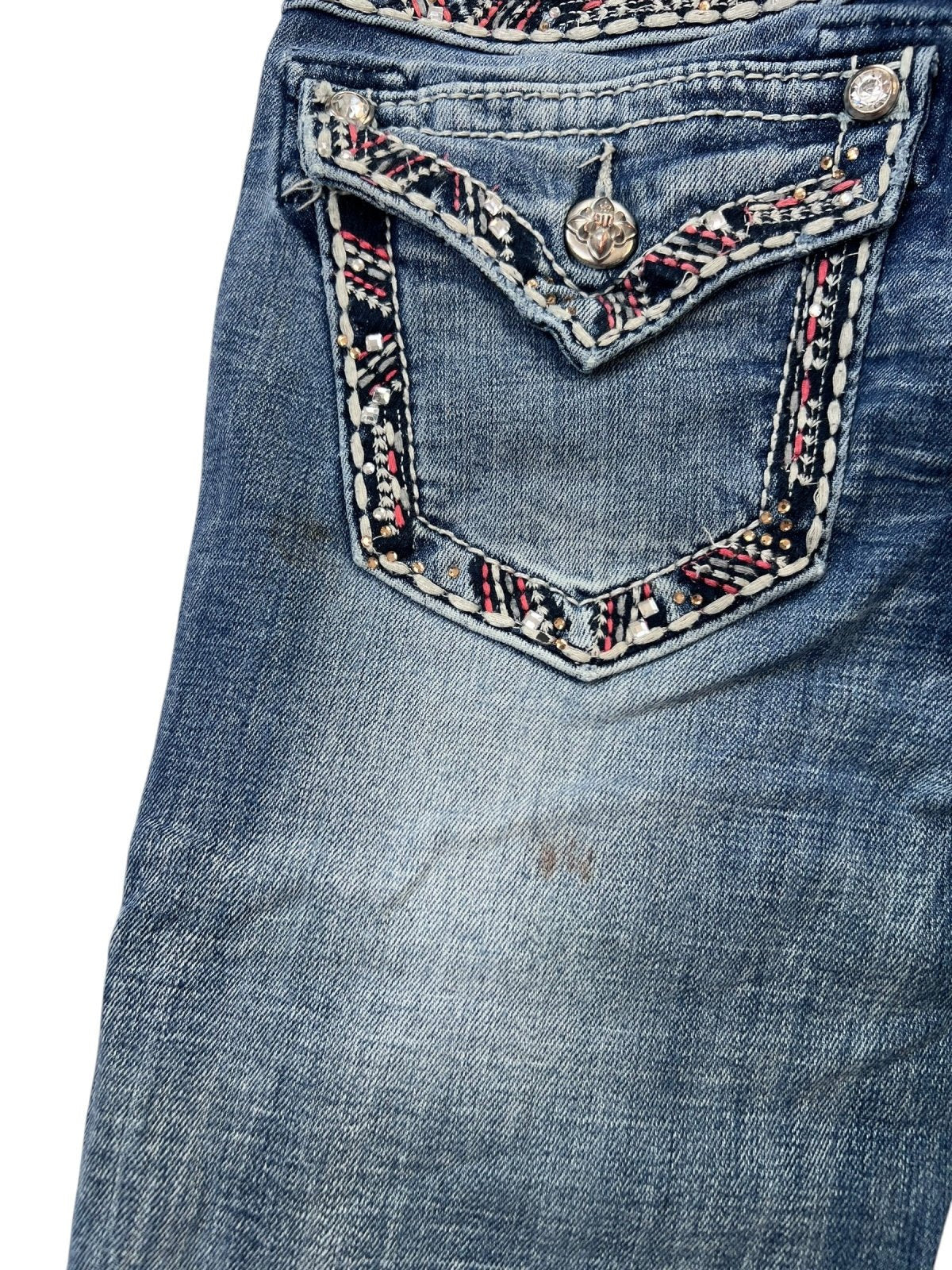 Nahaufnahme der Miss Me Low Rise Straight Jeans (W25 x L34) von ZAZA Resell in blauem Denim, mit einer Gesäßtasche mit roten, weißen und schwarzen Ziernähten, einem Metallknopf, verwaschenen Bereichen sowie Bundweite- und Außenbeinlängendetails für die Passform.