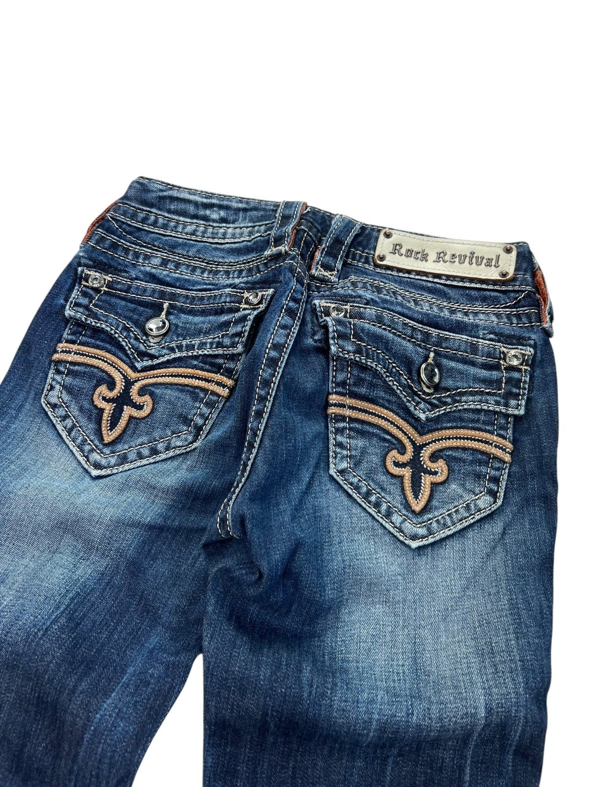 Eine Rock Revival Low Rise Boot Jeans (W24 x L30) von ZAZA Resell, von hinten gezeigt mit Fleur-de-Lis-Taschenstickerei, einem weißen Etikett über der rechten Tasche und einer stylischen Beinöffnung für eine perfekte Passform.