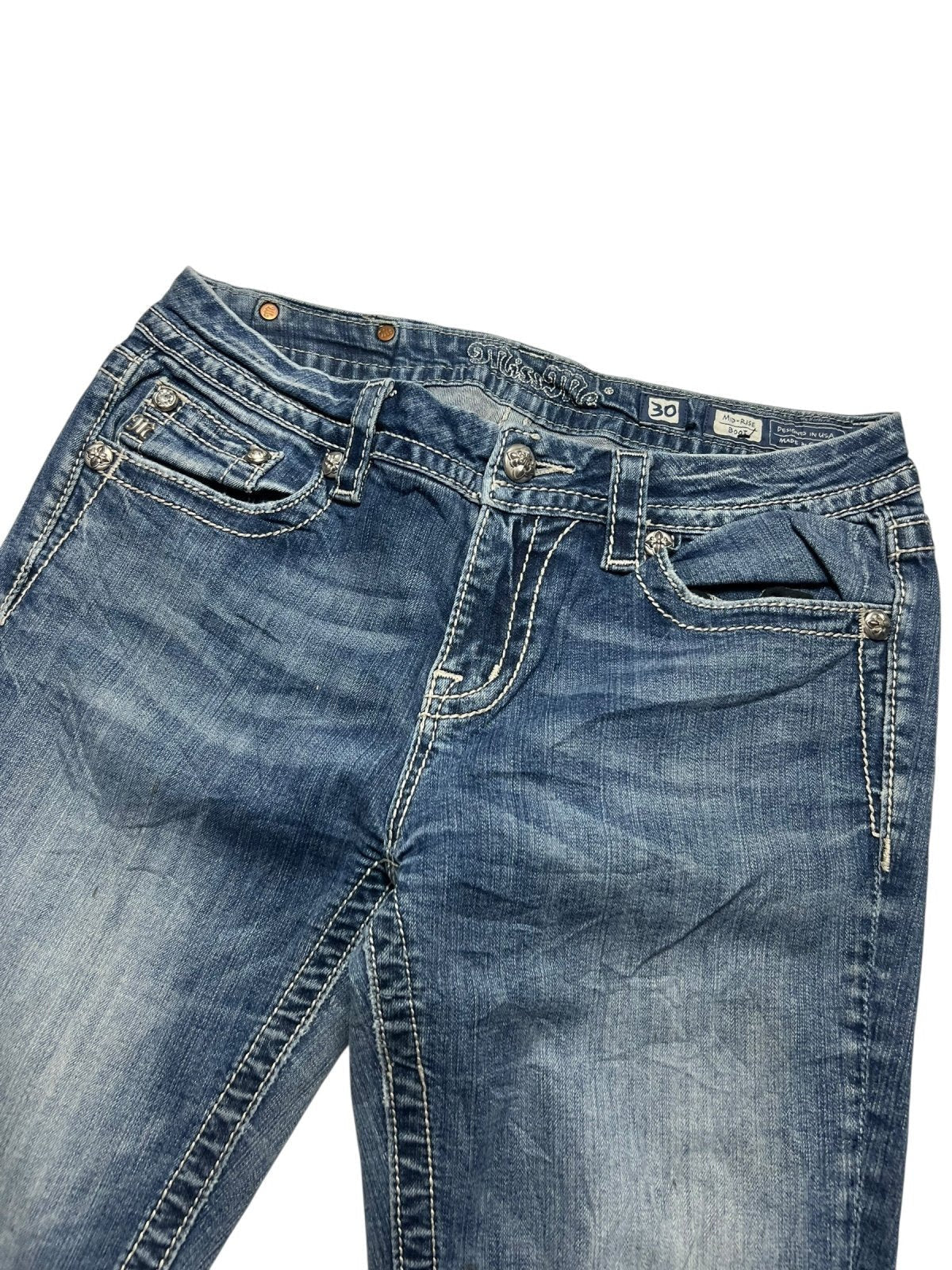 Die Miss Me Mid Rise Boot Jeans von ZAZA resell in Größe 30 (M) hat blauen Denim, weiße Kontrastnähte, Vordertaschen, Gürtelschlaufen und verblasste Oberschenkel. Die Jeans ist flach auf einem weißen Hintergrund abgebildet.
