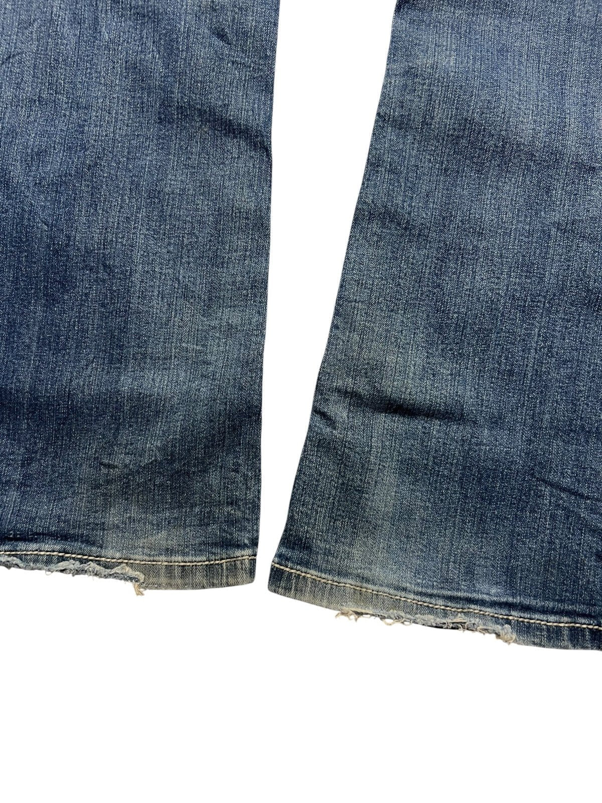 Nahaufnahme der ausgefransten Säume und des verblichenen Stoffs der Miss Me Mid Rise Boot Jeans (Größe 30, ZAZA resell), flach auf einen weißen Hintergrund gelegt, um die Außenbeinlänge und die vom Vintage-Stil inspirierten, abgenutzten Kanten hervorzuheben.