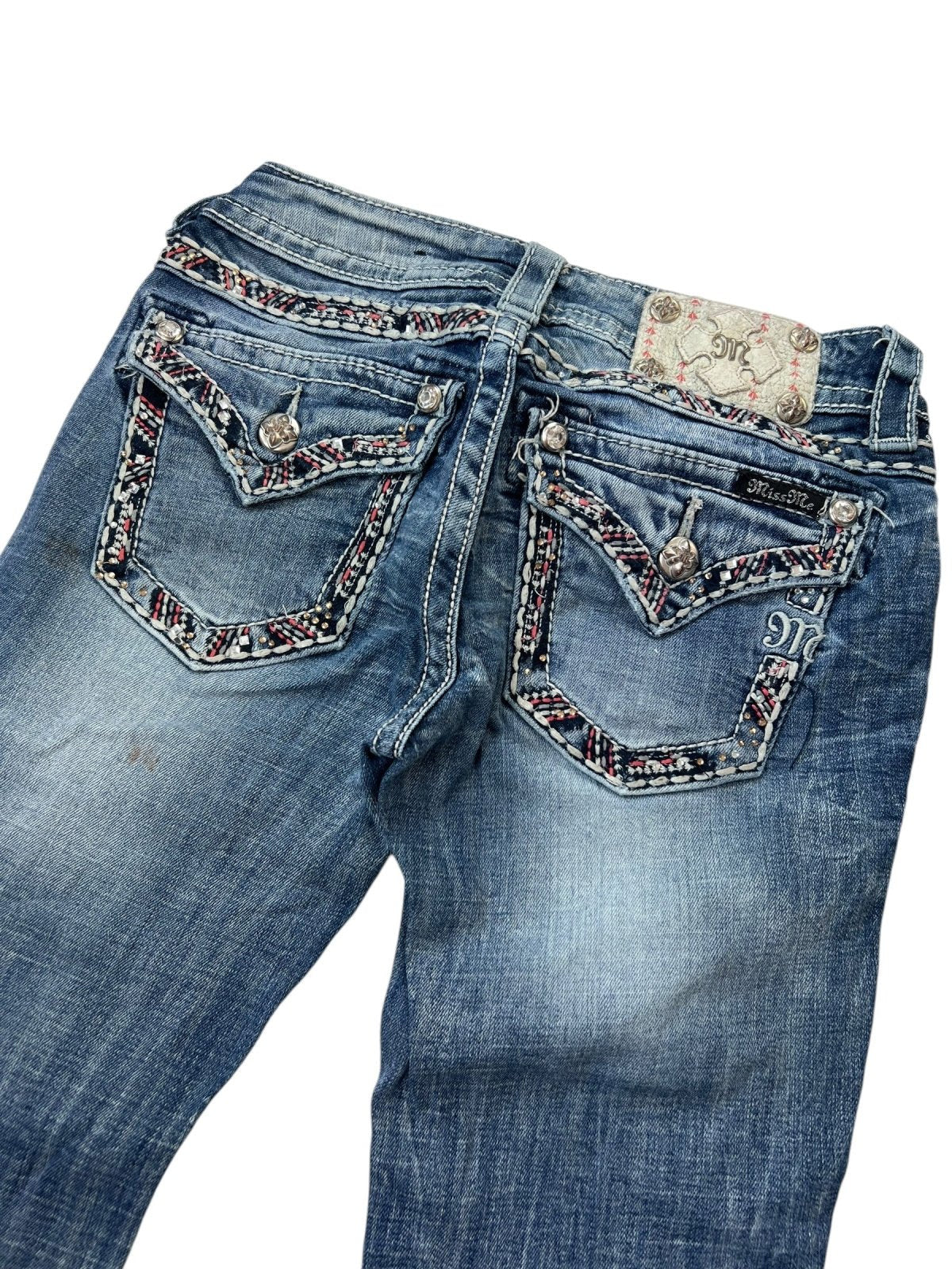 Die Miss Me Low Rise Straight Jeans von ZAZA Resell besteht aus blauem Denim mit Ziernähten, Metallknöpfen an den Gesäßtaschen, rot-weiß-schwarzen Stickereien auf den Taschen und einem weißen Bundetikett mit Blumenmuster. Größe: B25 x L34.