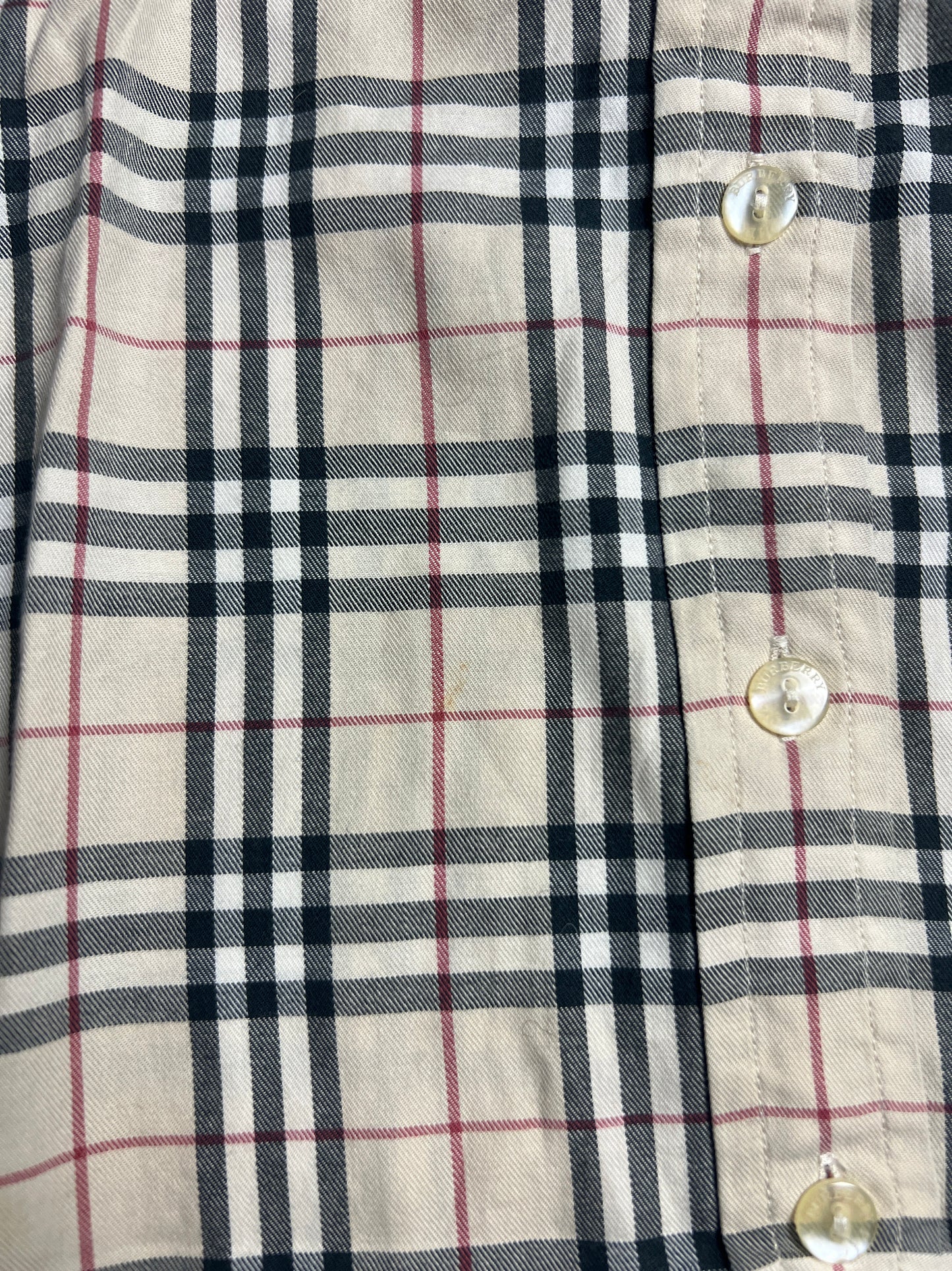 Nahaufnahme eines beigen Burberry Hemd | S aus dem ZAZA-Wiederverkauf, mit einem schwarz-weiß-roten Karomuster und drei durchsichtigen Knöpfen auf der rechten Seite. Zustand 9/10. Maße in cm und Labelgröße S auf Anfrage erhältlich.