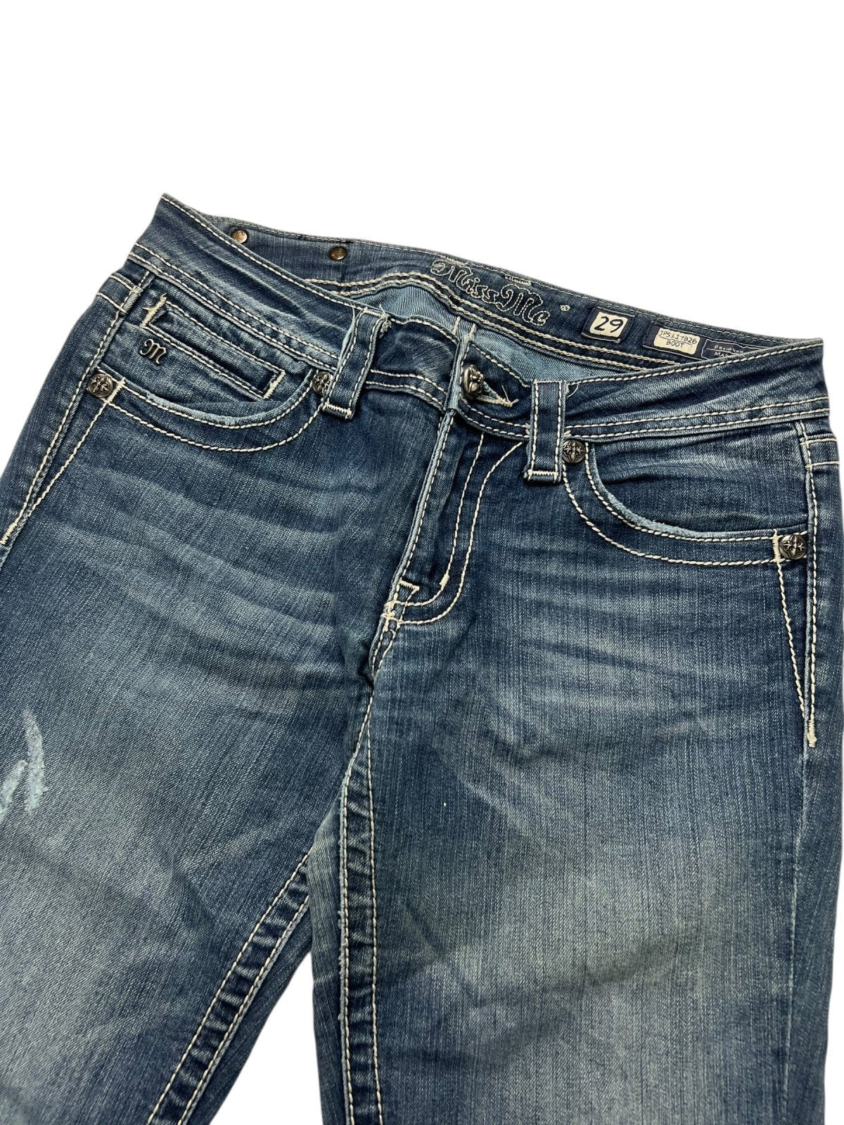 Ein Paar Miss Me Low Rise Boot Jeans in Größe 29 (M) von ZAZA resell, mit weißen Nähten und leichter Ausbleichung, gezeigt von der Taille bis zur Mitte des Oberschenkels auf weißem Hintergrund, mit Hervorhebung der Bundweite und präzisen Details der Labelgröße.