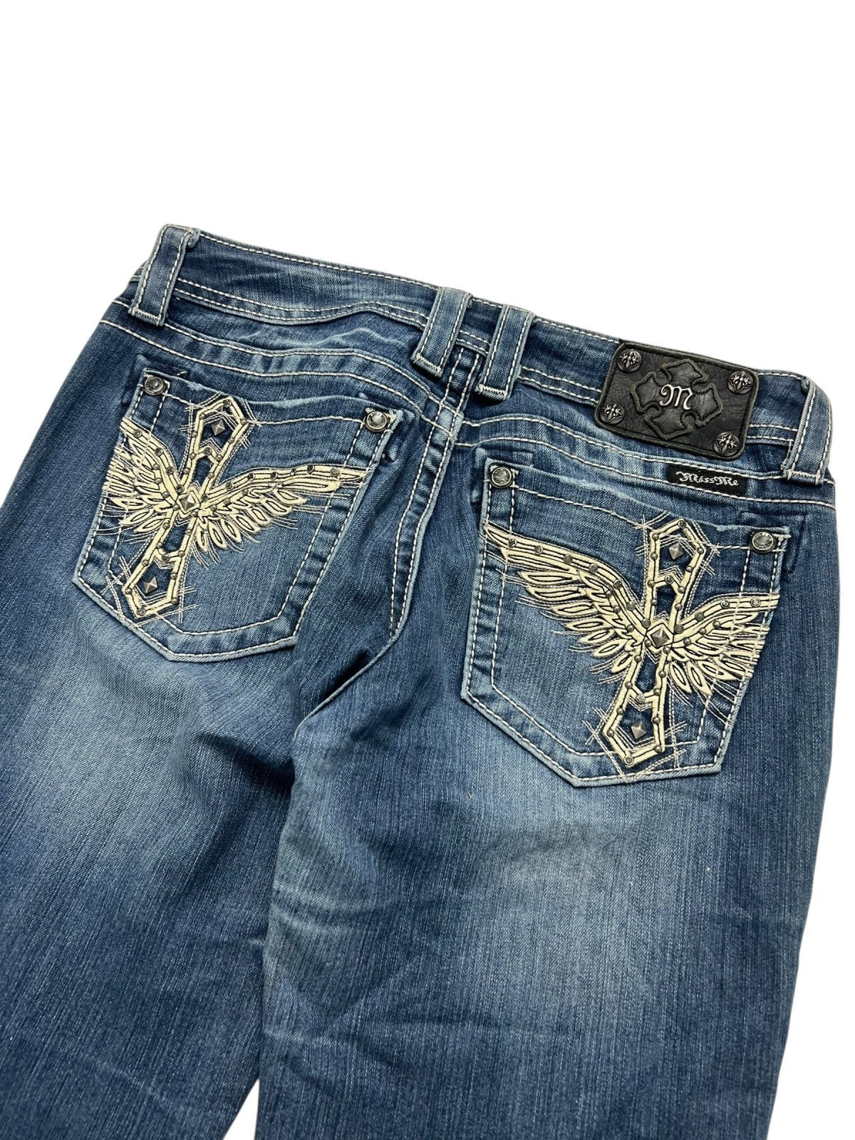 Miss Me Low Rise Boot Jeans von ZAZA resell in Größe 29 (M), mit blauem Denim, goldener Flügelstickerei auf den Gesäßtaschen, einem schwarzen Marken-Lederpatch über der rechten Tasche und präziser Bundweite für perfekten Sitz.
