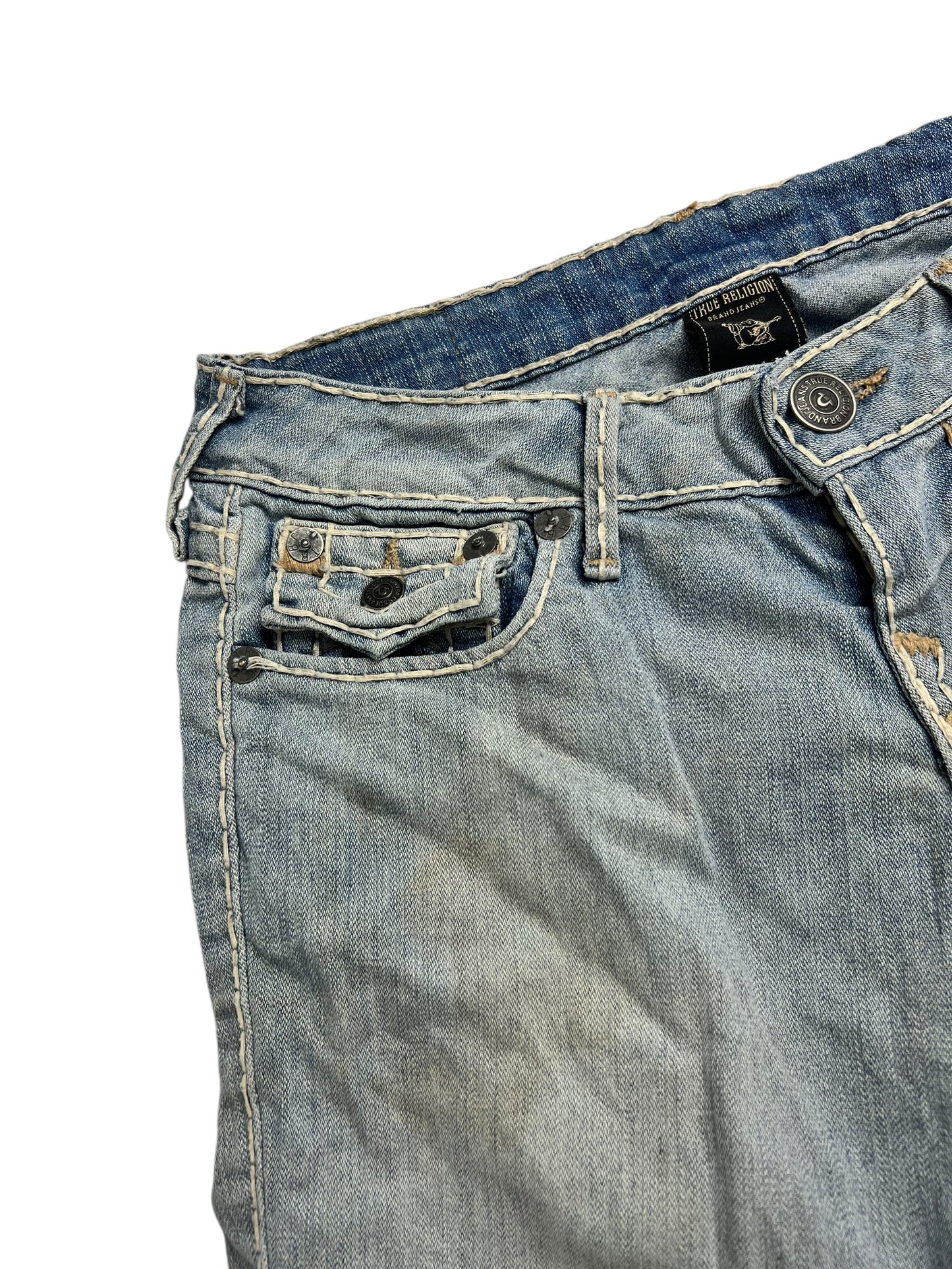 Eine Nahaufnahme der True Religion Billy Super T Low Rise Straight Jeans von ZAZA Resell (W26 x L28) in hellblauem Denim mit weißen Nähten, Bundweite, einer Vordertasche und einem Marken-Bundetikett mit leicht abgenutztem Look.