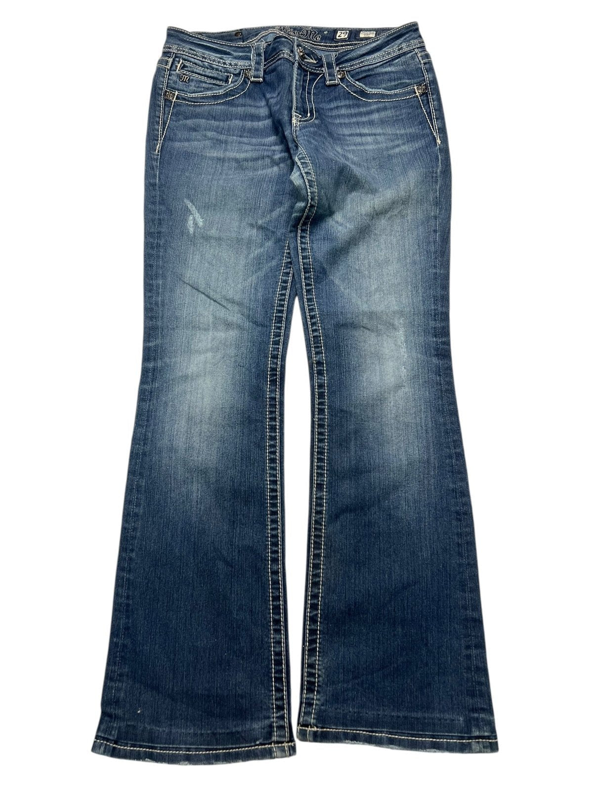 Die Miss Me Low Rise Boot Jeans von ZAZA resell, Größe 29 (M), hat blauen Denim mit weißen Nähten, verblasste Oberschenkel- und Kniedetails, fünf Taschen und eine Außenbeinlänge, die flach auf einem weißen Hintergrund gezeigt wird.