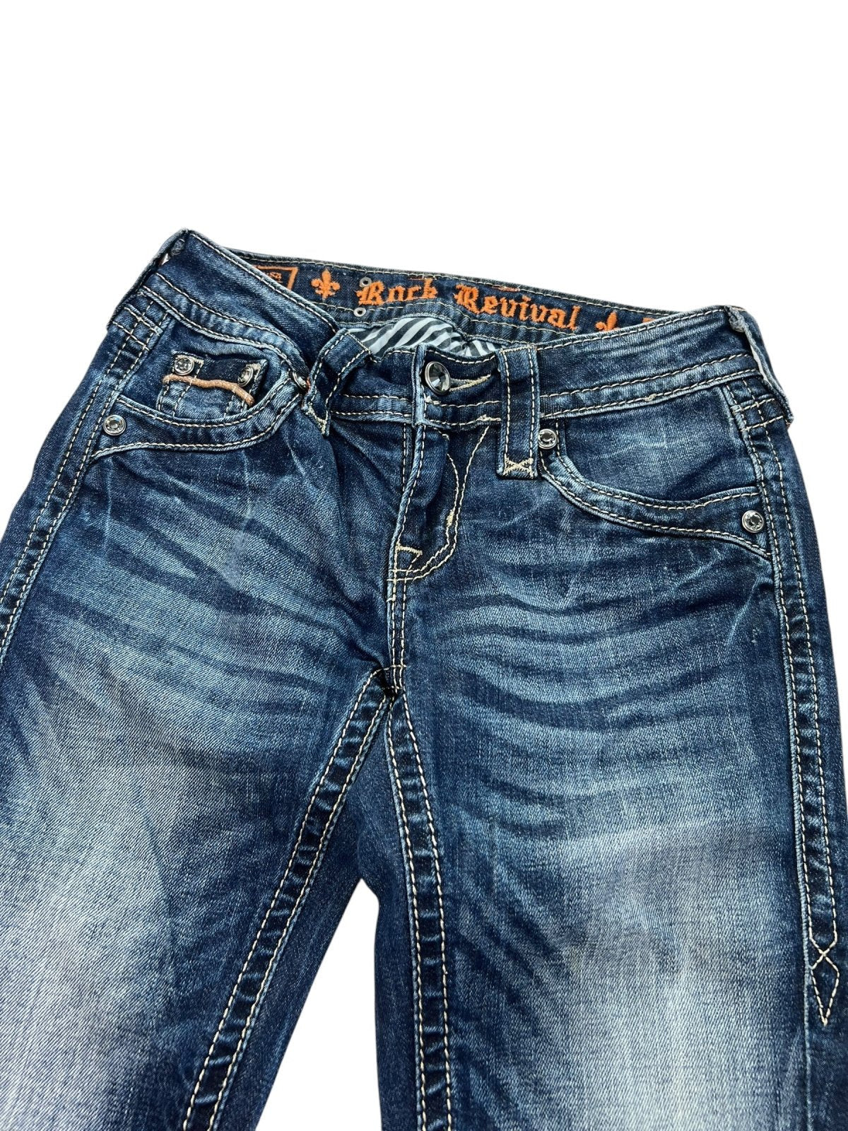 Ein Paar Rock Revival Low Rise Boot Jeans von ZAZA zum Weiterverkauf in der Größe W24 x L30, mit verblassten blauen und Used-Look-Details, orangefarbenen Nähten, sichtbaren Vordertaschen, Gürtelschlaufen und einem bequemen inneren Hosenbund mit Markenlogo.