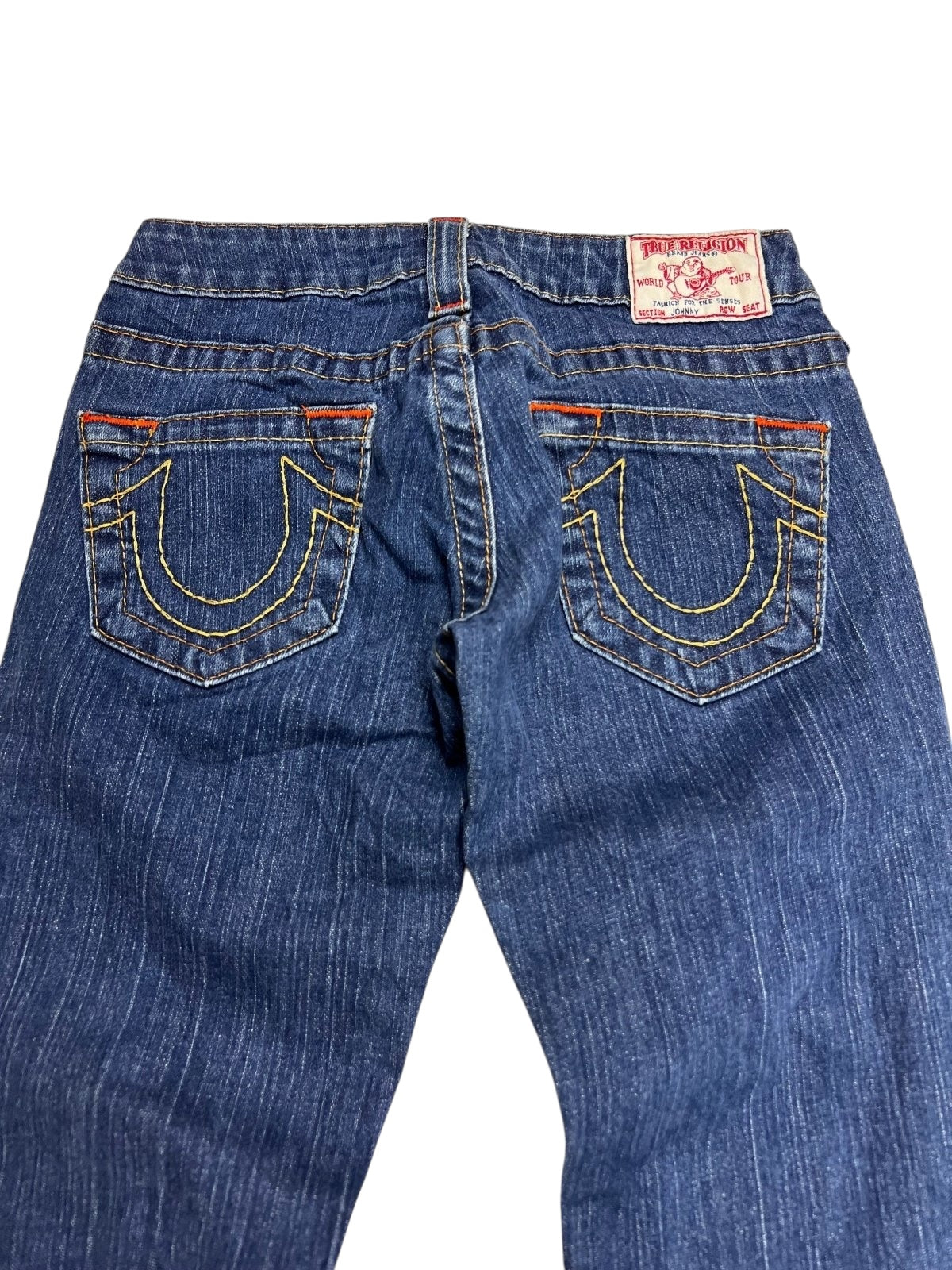 Eine True Religion Johnny Low Rise Straight Jeans (W24 x L30) von ZAZA Resell in Blau, von hinten abgebildet mit gelben Taschennähten und einem weiß-roten Etikett am Bund. Maße in cm und XS Zustand auf Anfrage.