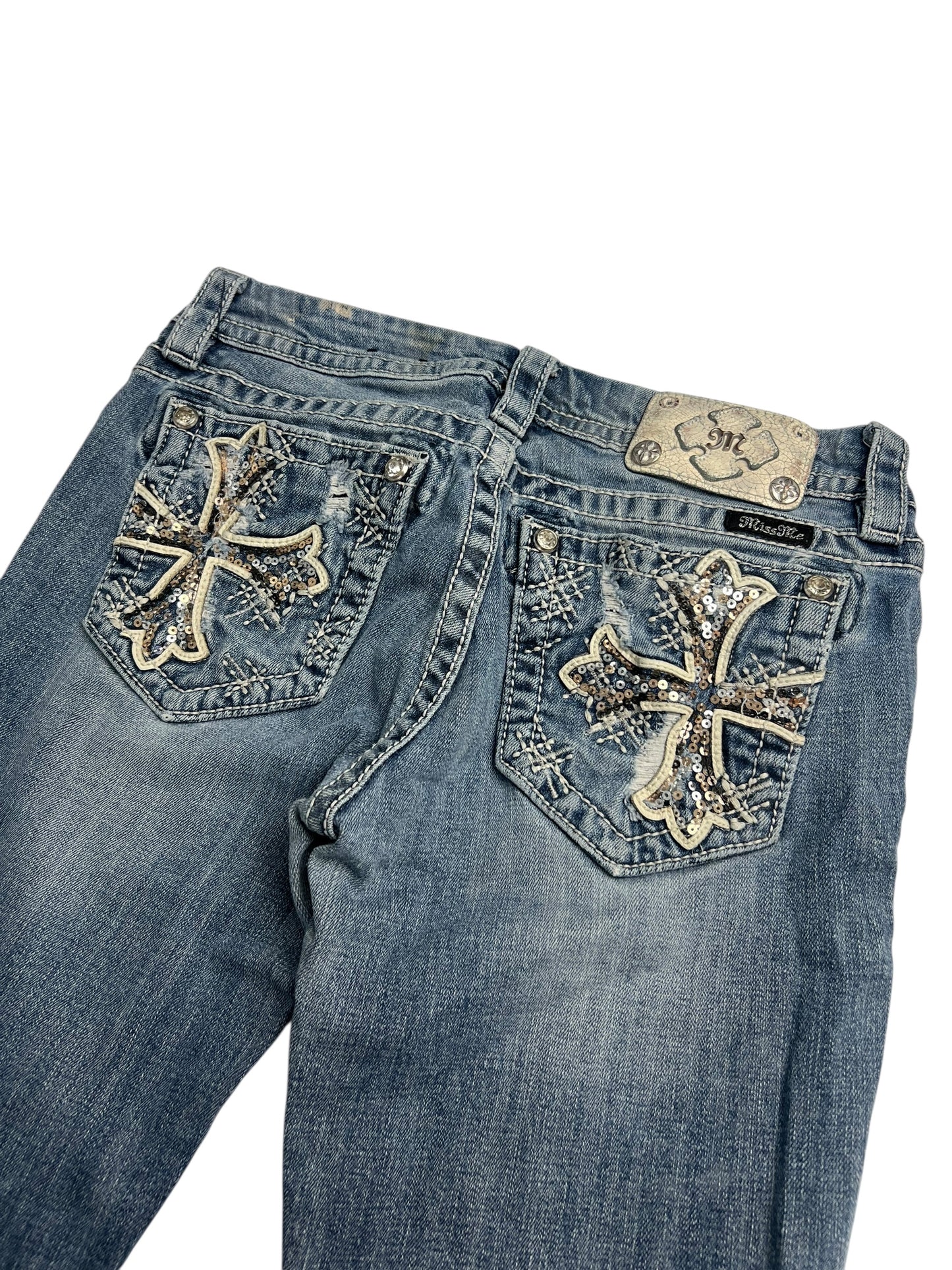 Die Miss Me Mid Rise Boot Jeans von ZAZA resell (W28 x L26) besteht aus blauem Denim mit silbernen und weißen Kreuzdesigns, Strasssteinen, Ziernähten an den Gesäßtaschen, einem Markenaufnäher aus Leder und verwaschenen Details. Erhältlich in verschiedenen Labelgrößen.