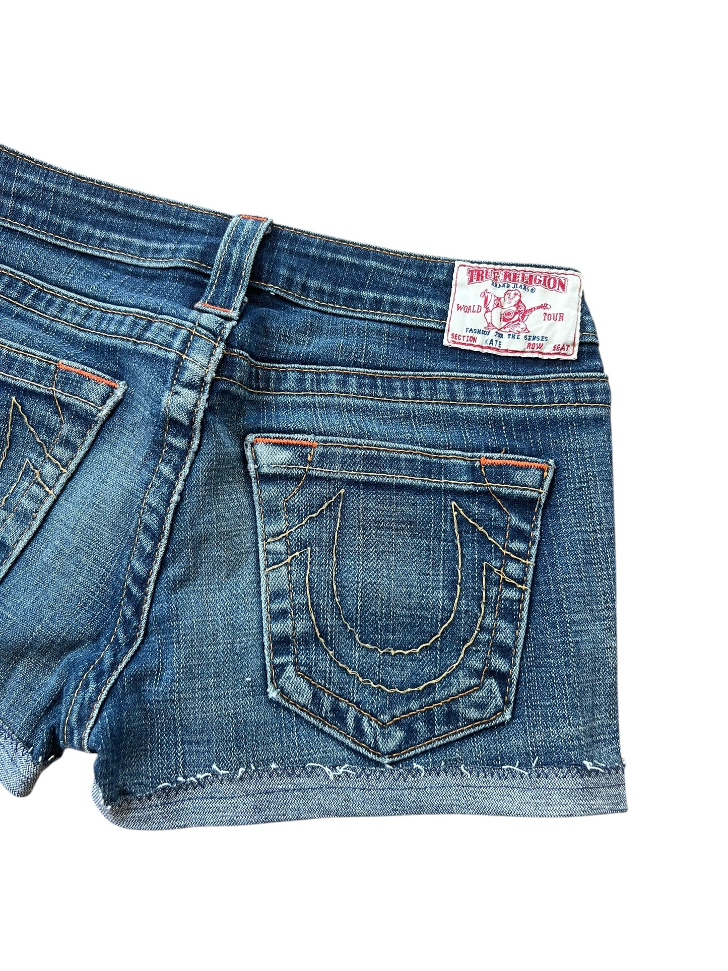 True Religion Shorts | 27 (S) von ZAZA wiederverkaufen: Shorts aus blauem Denim mit ausgefransten Säumen, orangefarbenen Nähten, einem weiß-roten Markenaufnäher am Bund und einer charakteristischen hufeisenförmigen Naht an der Gesäßtasche. Bundweite 37.