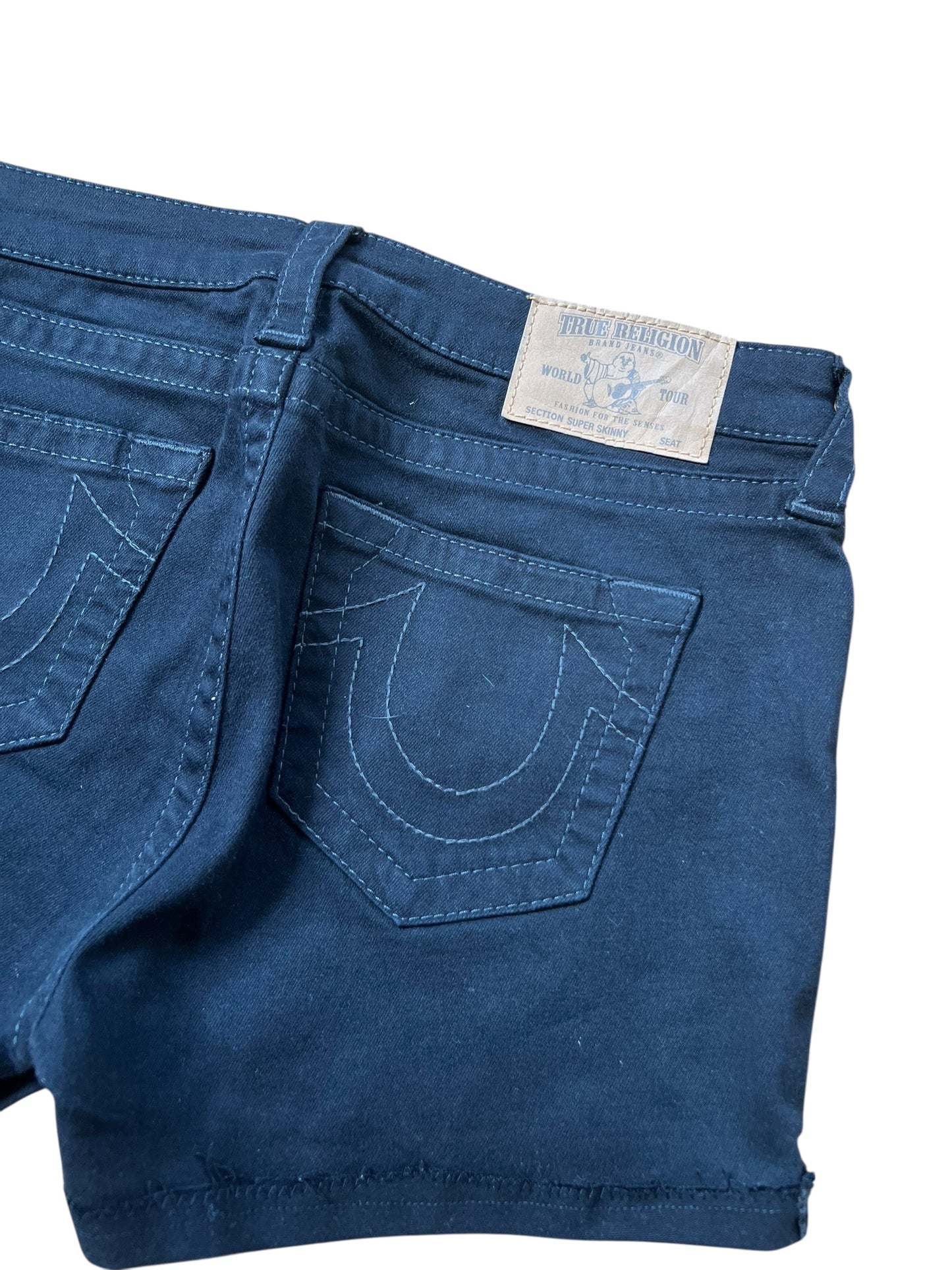 Eine Nahaufnahme der dunkelblauen True Religion Shorts (Größe 29/S) aus dem ZAZA-Wiederverkauf, die Gesäßtaschen mit weißen Nähten und ein Markenetikett am Bund zeigt.