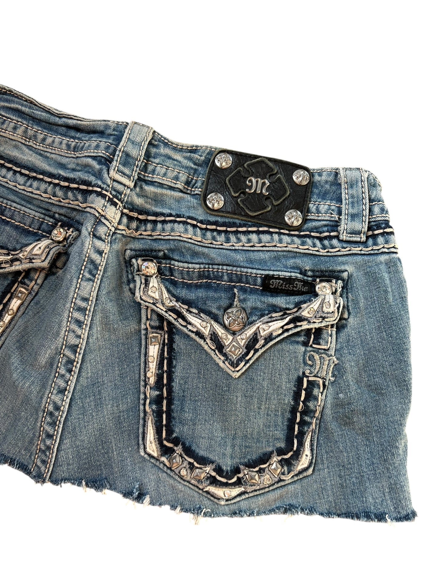 Nahaufnahme der Rückseite des blauen Miss Me Rocks in Größe 31 (M) von ZAZA resell mit Ziernähten, strassbesetzten Taschen und einem schwarzen Markenaufnäher aus Leder mit silbernen Nieten am Bund.