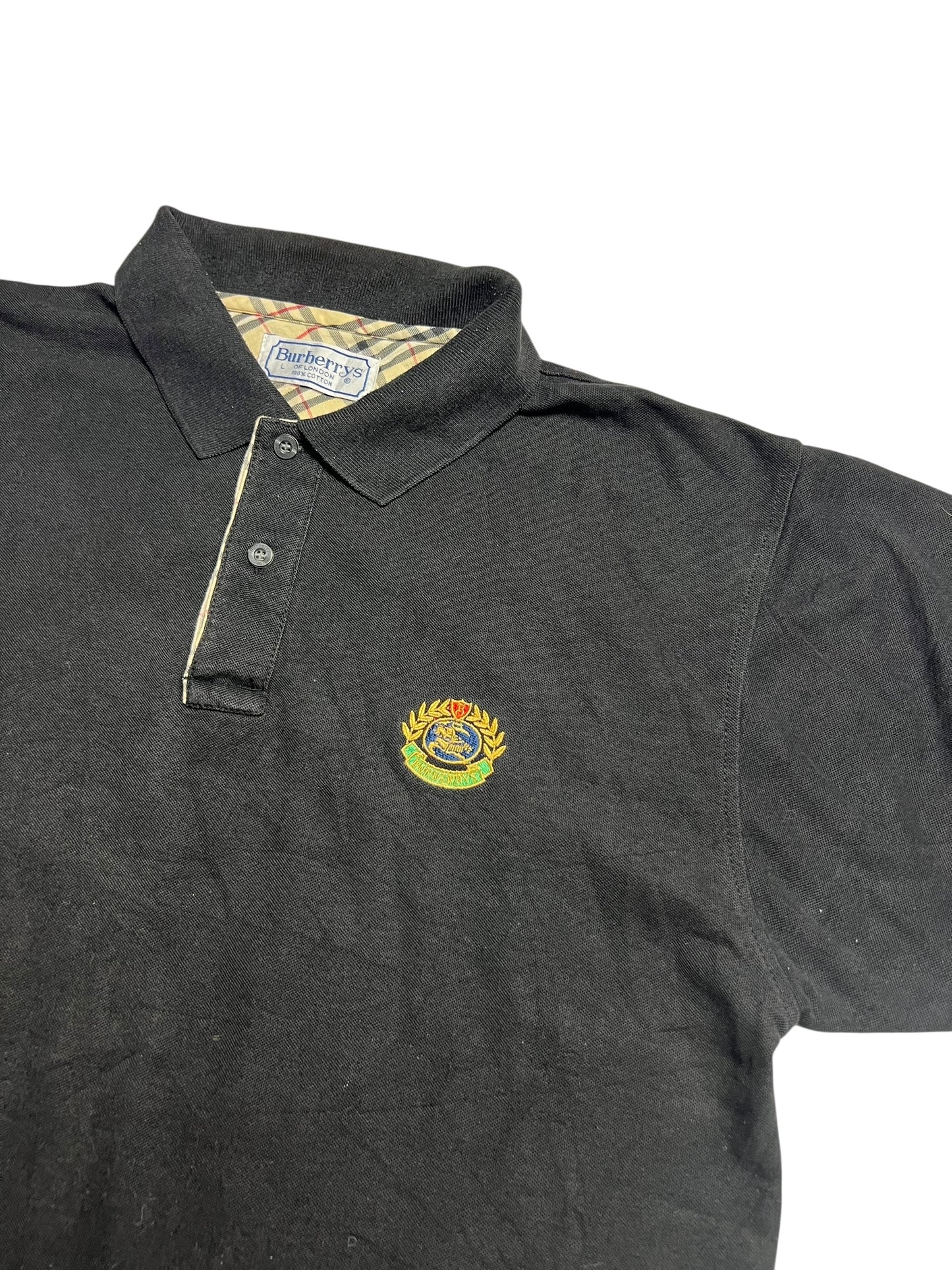 Burberry Polo Shirt | L von ZAZA resell: schwarz mit Kragen, Knopfleiste, gesticktem Wappenlogo auf der Brust, karierter Kragen mit Burberrys Label. Zustand 9/10. Labelgröße L. Maße in cm auf Anfrage.