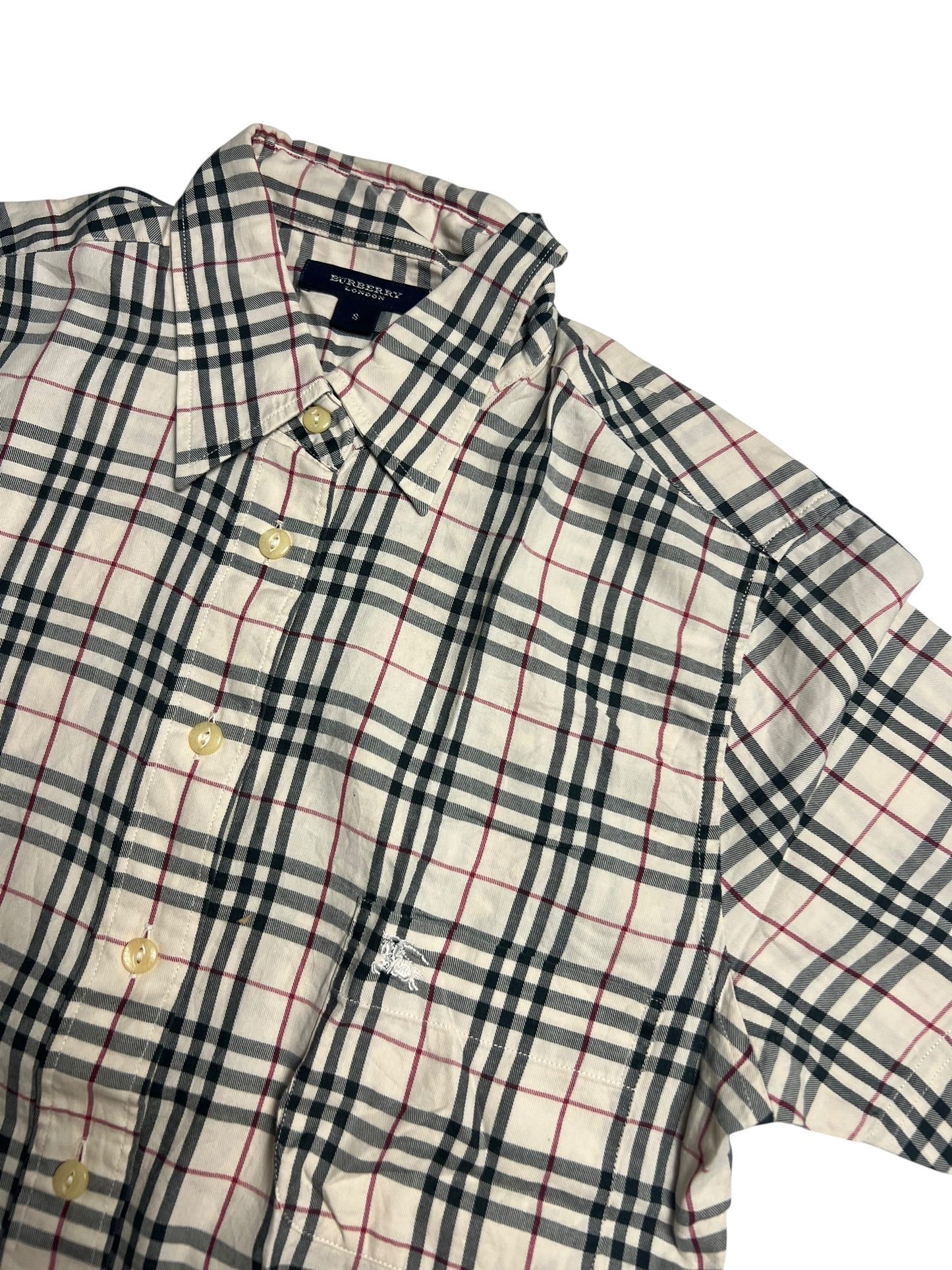 Das Burberry Hemd | S von ZAZA resell hat kurze Ärmel, klassische beige/schwarz/rote Karos, cremefarbene Knöpfe, eine Vordertasche und Zustand 9,5/10. Maße in cm auf Anfrage. Liegt flach auf einem weißen Hintergrund.