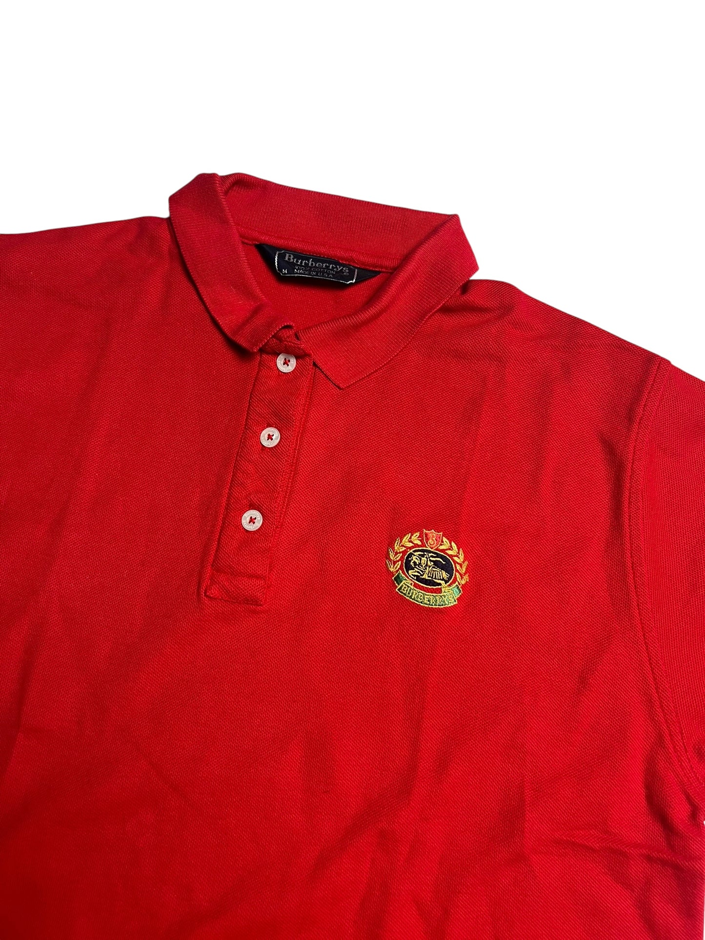 Ein rotes Burberry Polo Shirt (M) von ZAZA resell mit Kragen, drei Knöpfen und gesticktem schwarzen Pferdewappen mit grünem Lorbeer auf der linken Brust. Zustand 9/10. Maße in Zentimetern auf Anfrage.