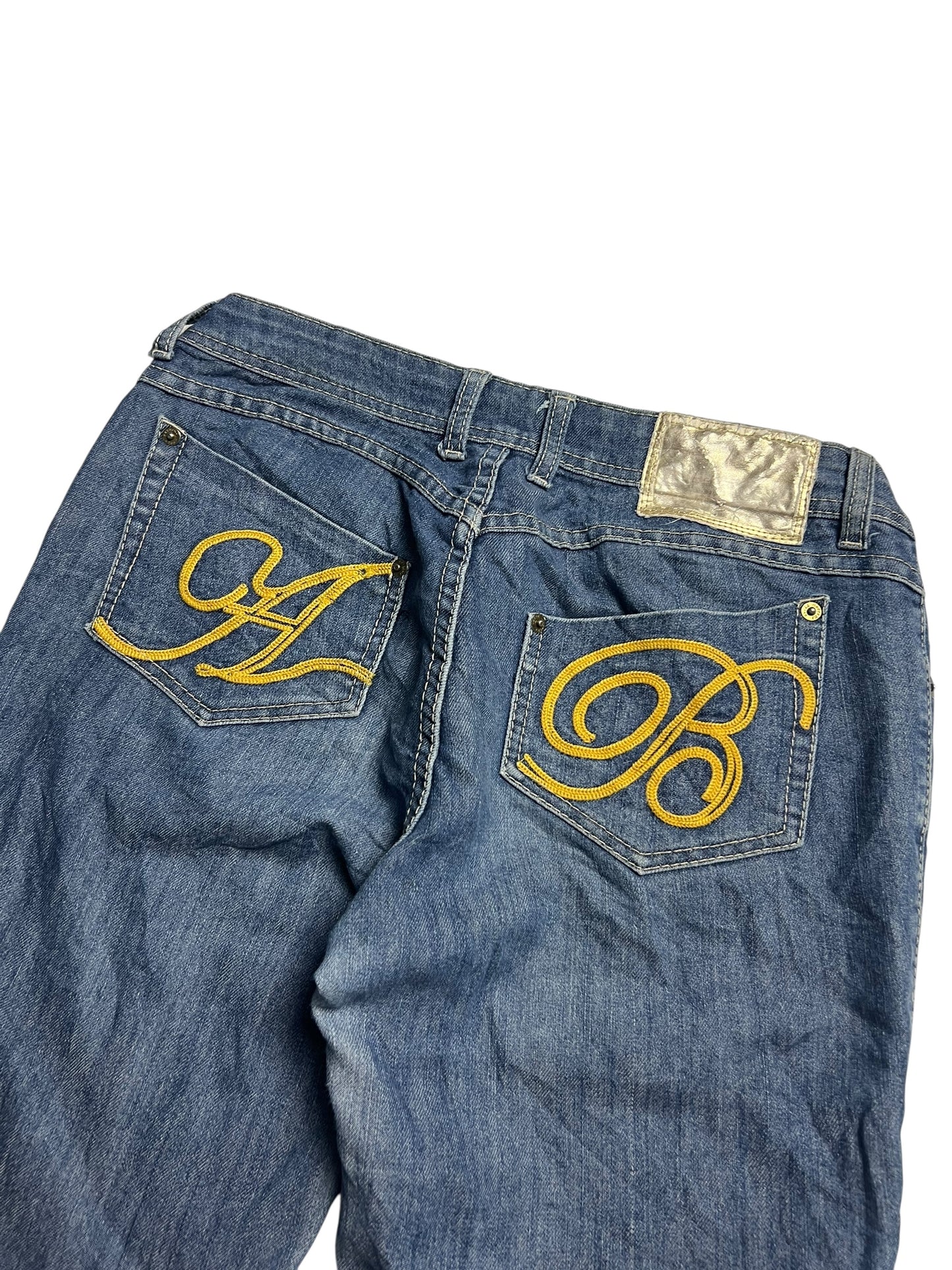 Die Apple Bottoms Mid Rise Boot Jeans von ZAZA resell hat ein großes gelbes gesticktes A und B auf den Gesäßtaschen, ein silberfarbenes gemustertes Bundlabel, Bundweite Passformdetails und bequemen, strapazierfähigen Stoff.