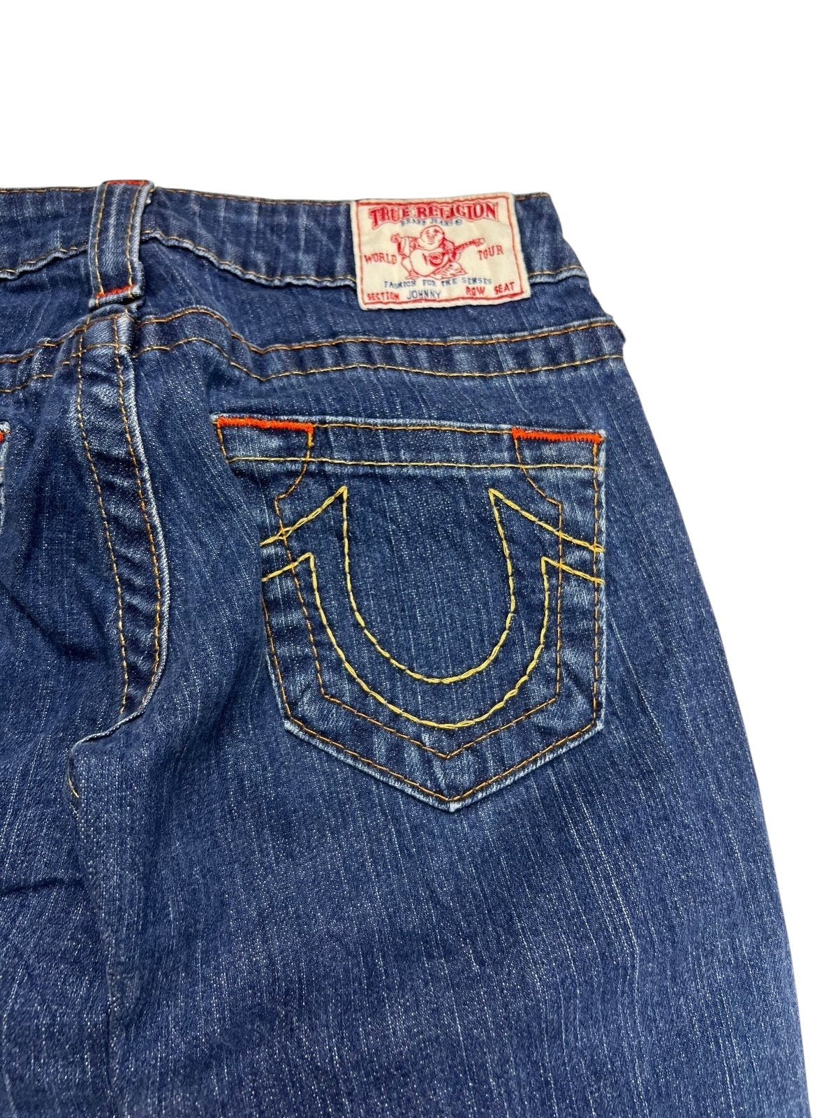 Nahaufnahme der Gesäßtasche der True Religion Johnny Low Rise Straight Jeans (W24 x L30) von ZAZA Resell, blau mit gelben Nähten und rotem Logo-Patch darüber, Maße in cm und XS-Zustand verfügbar.