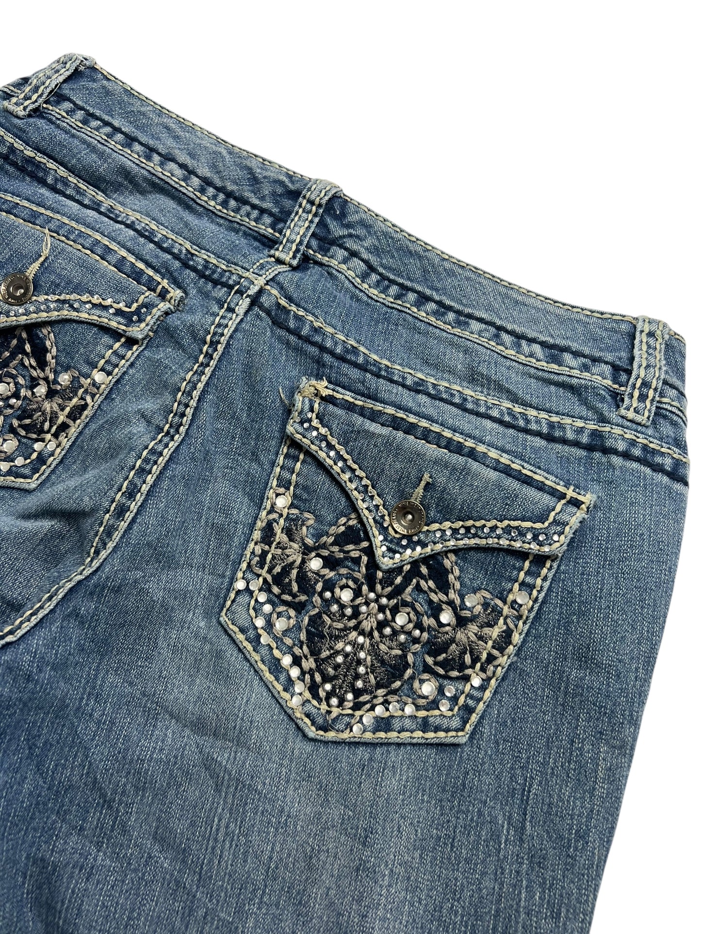Nahaufnahme der Nine West Mid Rise Boot Jeans (W31 x L33) von ZAZA Resell, aus blauem Denim mit dekorativen Gesäßtaschen, aufwendiger Stickerei und Details an den Hosenbeinen für einen stylischen, beliebten Look.