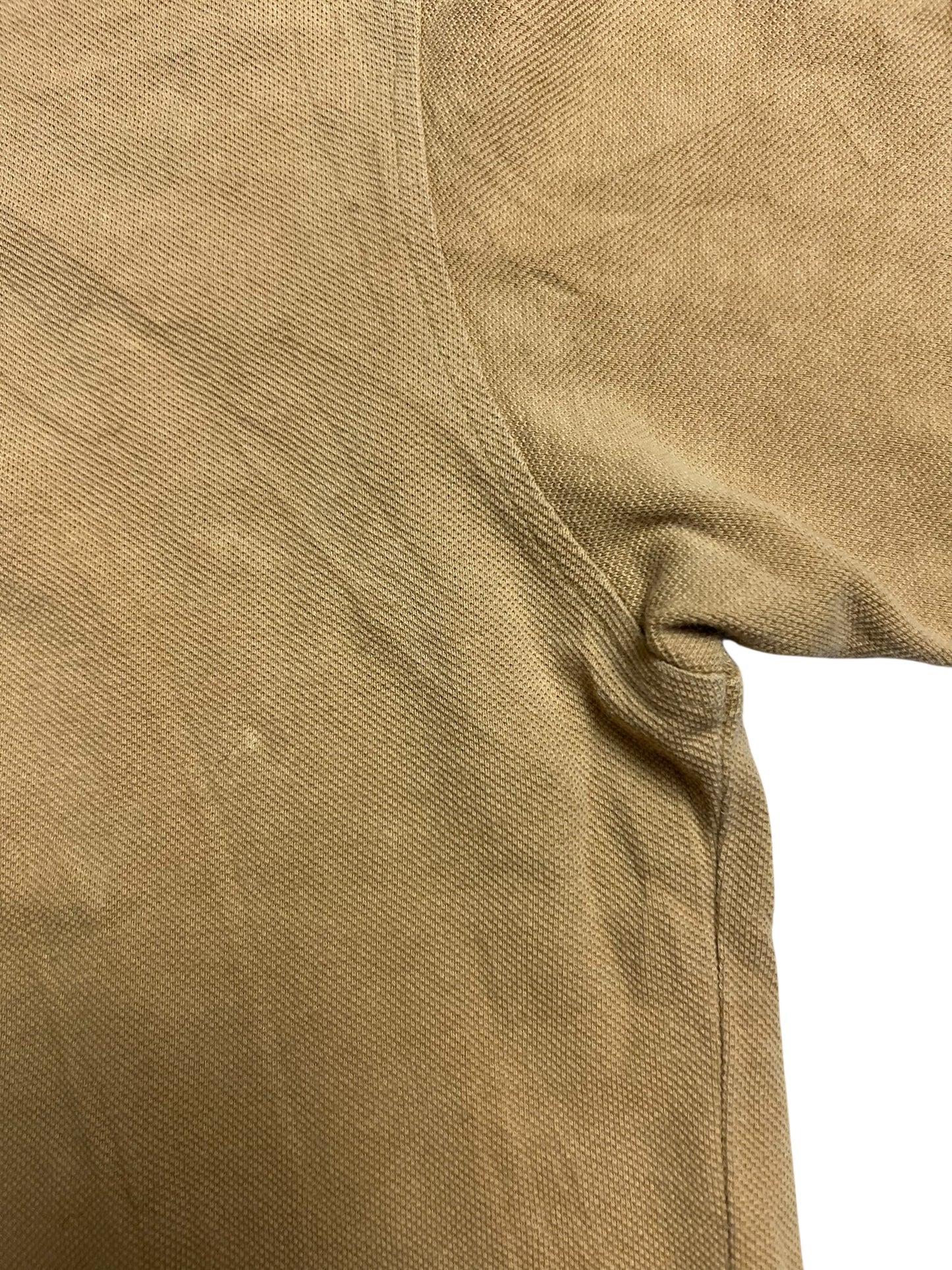 Nahaufnahme eines hellbraunen, strukturierten Burberry Polo Shirts (ZAZA resell), Größe M, mit Hervorhebung der Achselhöhle und der Ärmelnaht auf weißem Hintergrund. Zustand 9/10.