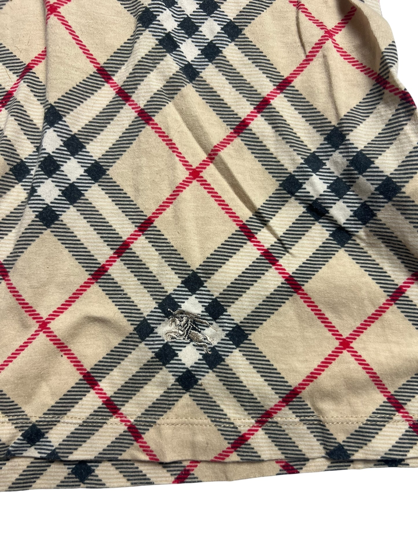Das Burberry Polo Shirt | S von ZAZA resell ist ein beiger Stoff mit schwarzen, weißen und roten Karos. Es hat ein ausgefranstes Loch in der Nähe der Mitte, das beschädigte Fäden freilegt. Der Zustand wird mit 5/10 bewertet.