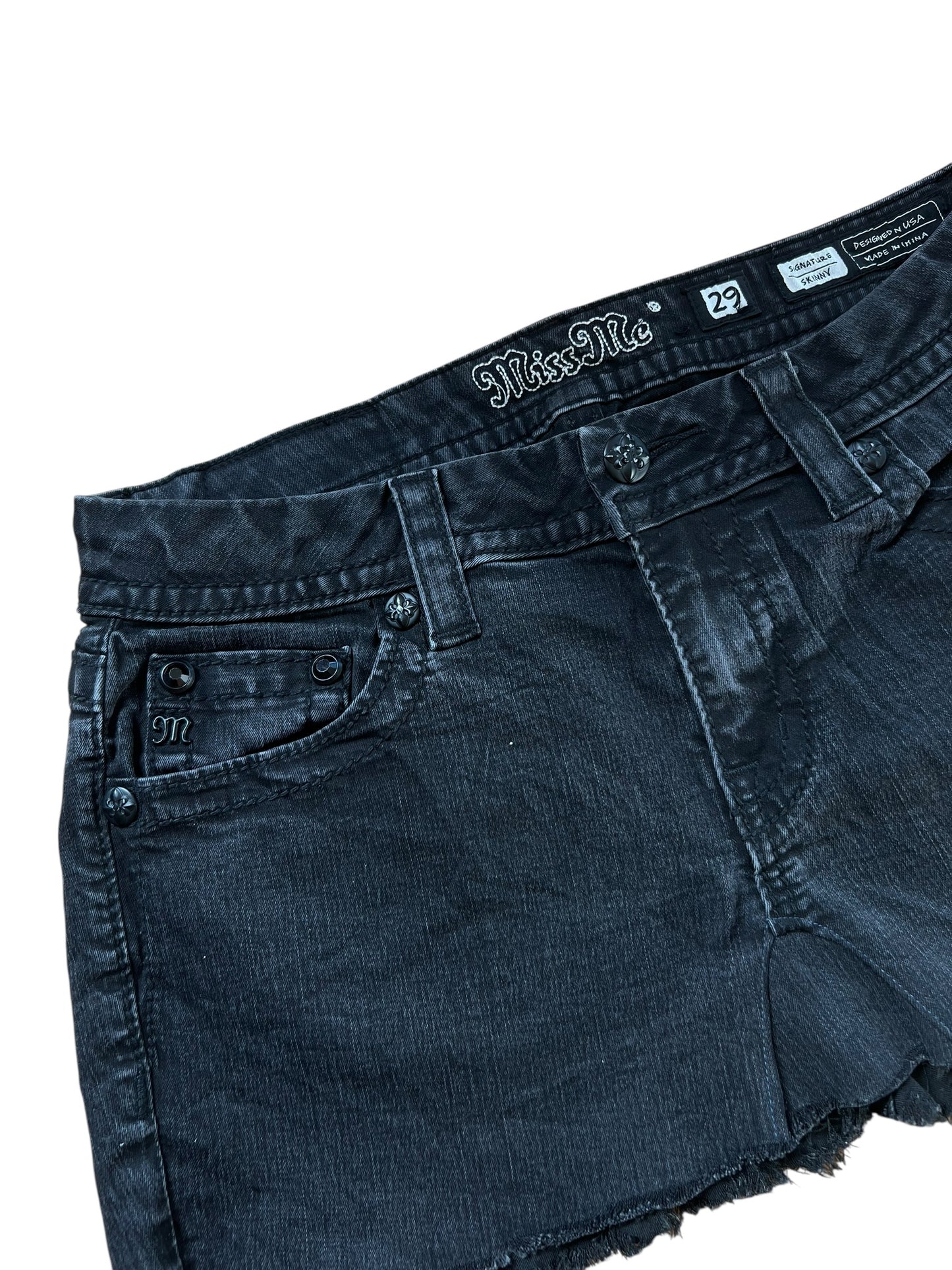 Nahaufnahme eines schwarzen Miss Me Rocks aus Denim (Größe 29/M) von ZAZA resell mit ausgefransten Säumen, Metallnieten, Nahtdetails und einem Bund mit Markenzeichen.