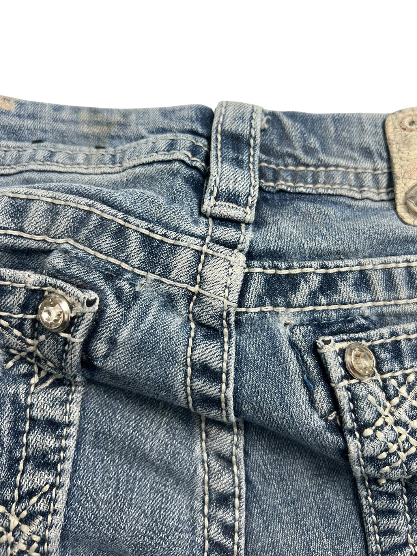 Nahaufnahme des Hosenbunds und der Gürtelschlaufe der Miss Me Mid Rise Boot Jeans (W28 x L26) von ZAZA Resell mit detaillierten Nähten, Metallnieten, gestickten Taschendesigns und Bundweite-Informationen für eine ideale Passform.