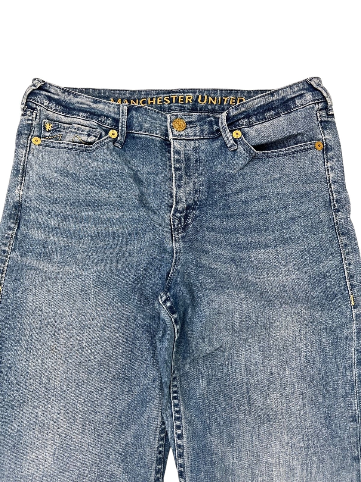 True Religion x Manchester United Mid Rise Flare Jeans von ZAZA aus blauem Denim mit goldenen Knöpfen, Nieten und „MANCHESTER UNITED“ in Gold auf der Innenseite des Hosenbunds. Seltenes Modell, Größe W34 x L30, Zustand 9/10. Maße auf Anfrage.