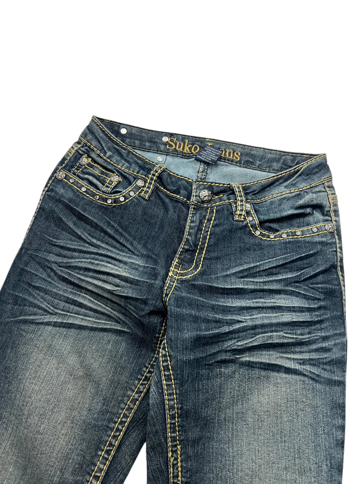 Ein Paar Suko Jeans Mid Rise Boot (B26 x L34) von ZAZA Resell, blauer Denim mit gelben Nähten, verwaschenen und Used-Look-Details, „Suko Jeans“ auf dem inneren Bund. Flach auf weißem Hintergrund liegend, Bundweite und Beinöffnung sichtbar.