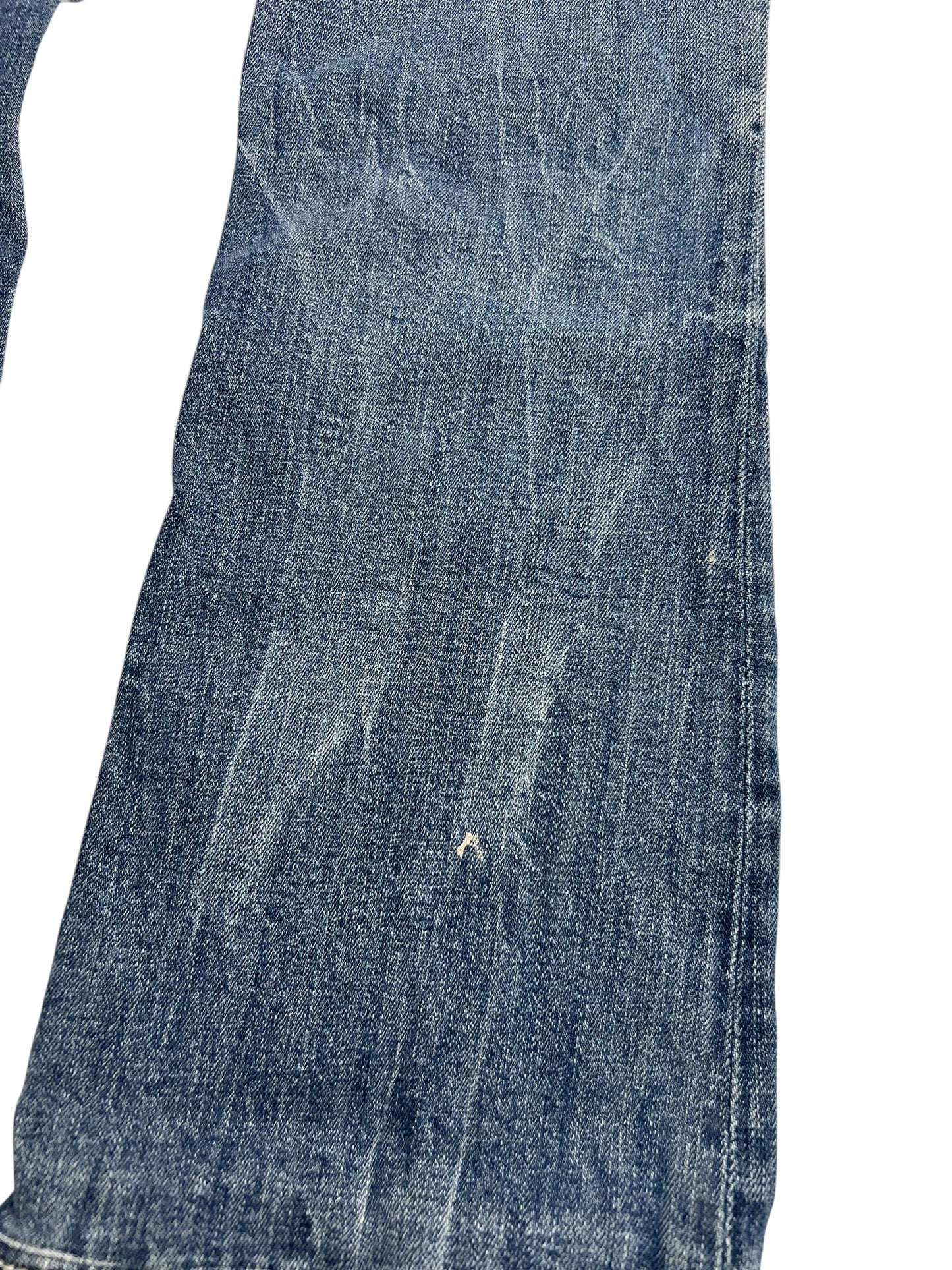 Eine Nahaufnahme der Miss Me Mid Rise Boot Jeans (W28 x L26) von ZAZA Resell zeigt blauen Denim mit Ausbleichungen, Bügelfalten, einem weißen Fleck und sichtbaren Bundweite-Details vor einem weißen Hintergrund.