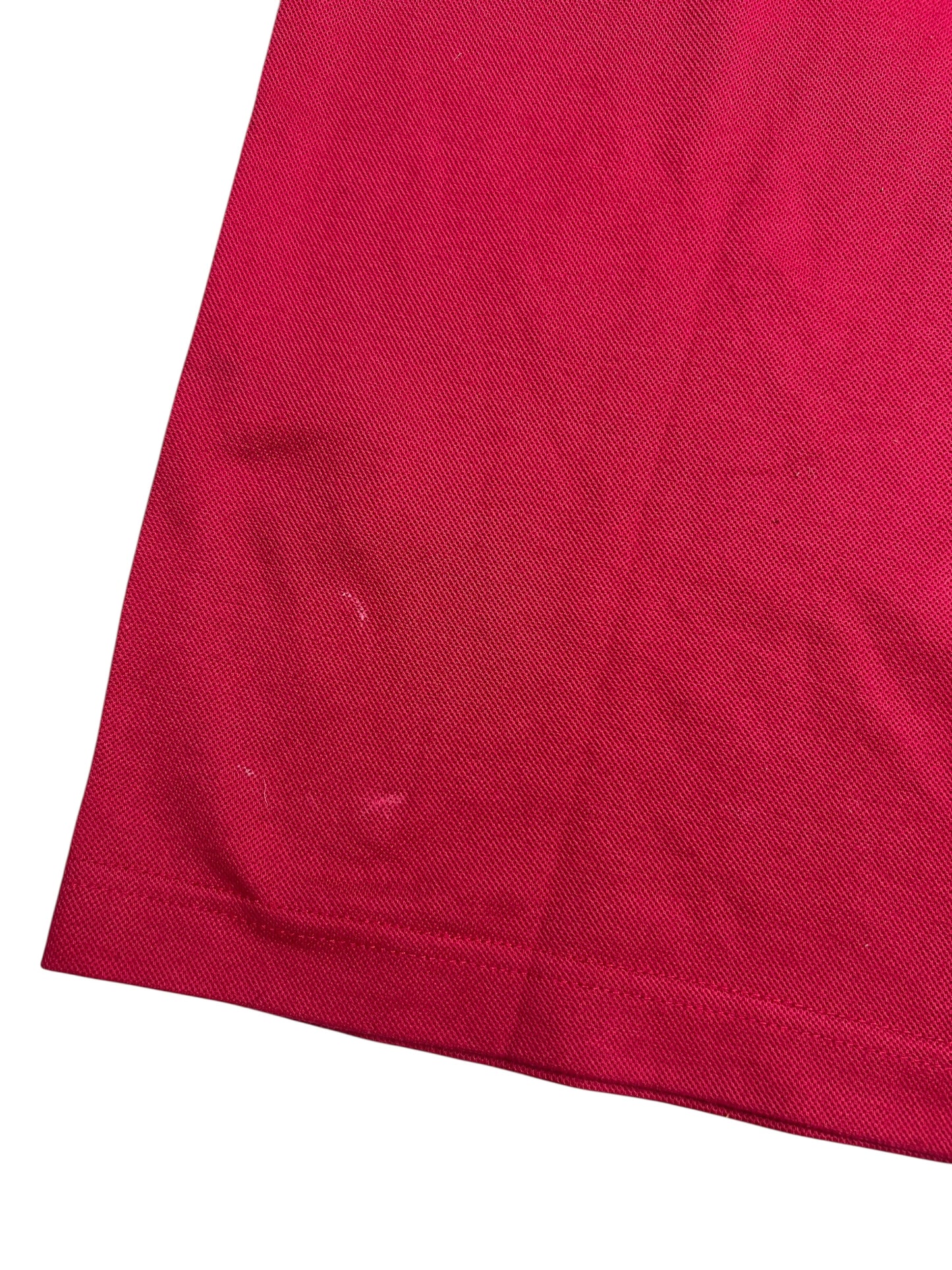 Nahaufnahme der unteren Ecke eines roten Burberry Polo Shirts (L) von ZAZA resell, die einen schwachen Lichtfleck in der Nähe des Saums zeigt. Zustand: 8/10.