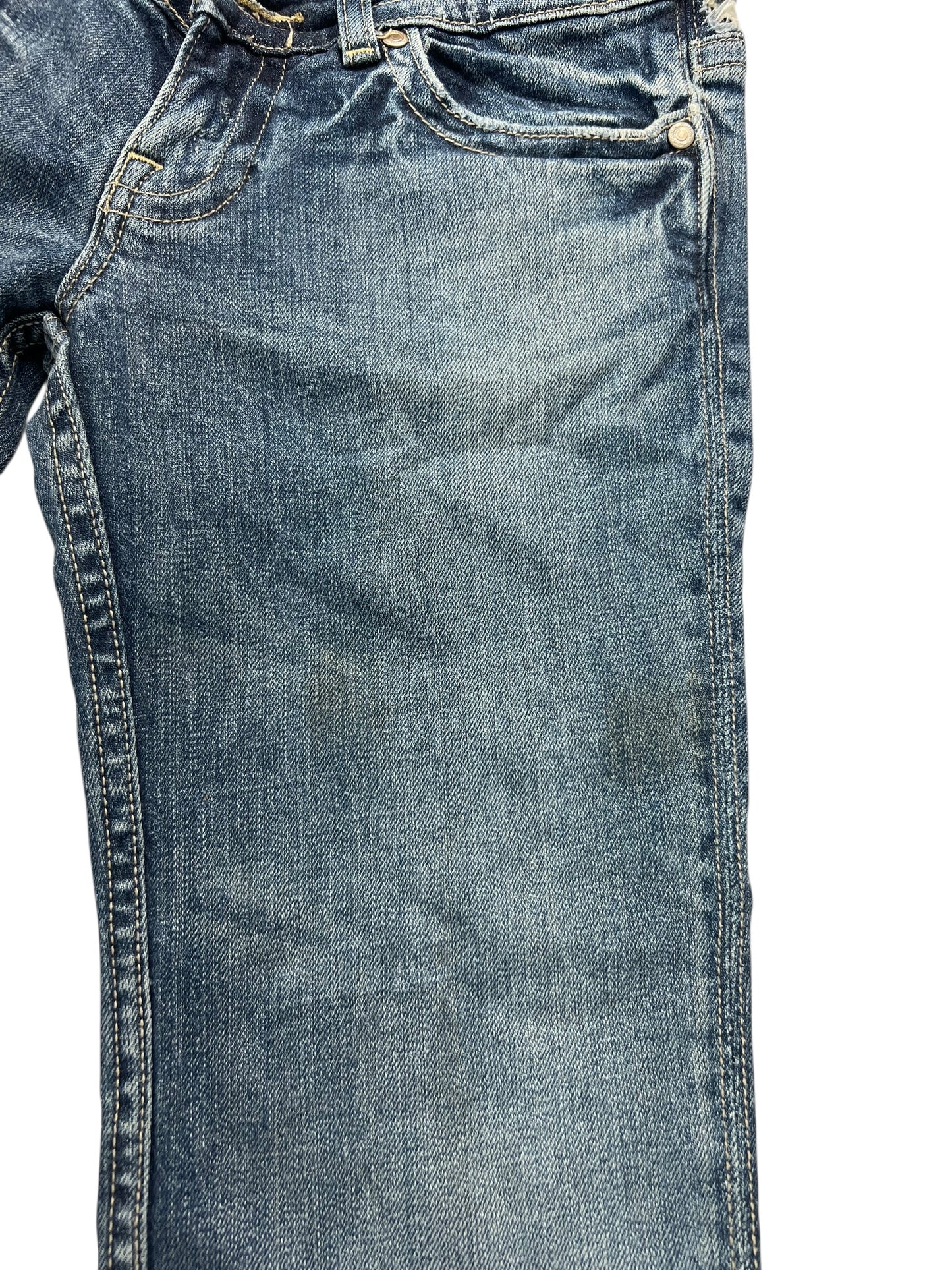Eine Nahaufnahme der Miss Me Low Rise Boot Jeans (B26 x L31) von ZAZA Resell zeigt den oberen Vorderbereich mit Tasche, Knopf und Gürtelschlaufe. Der blaue Denim hat einen leicht abgenutzten Look und schwache dunkle Flecken.
