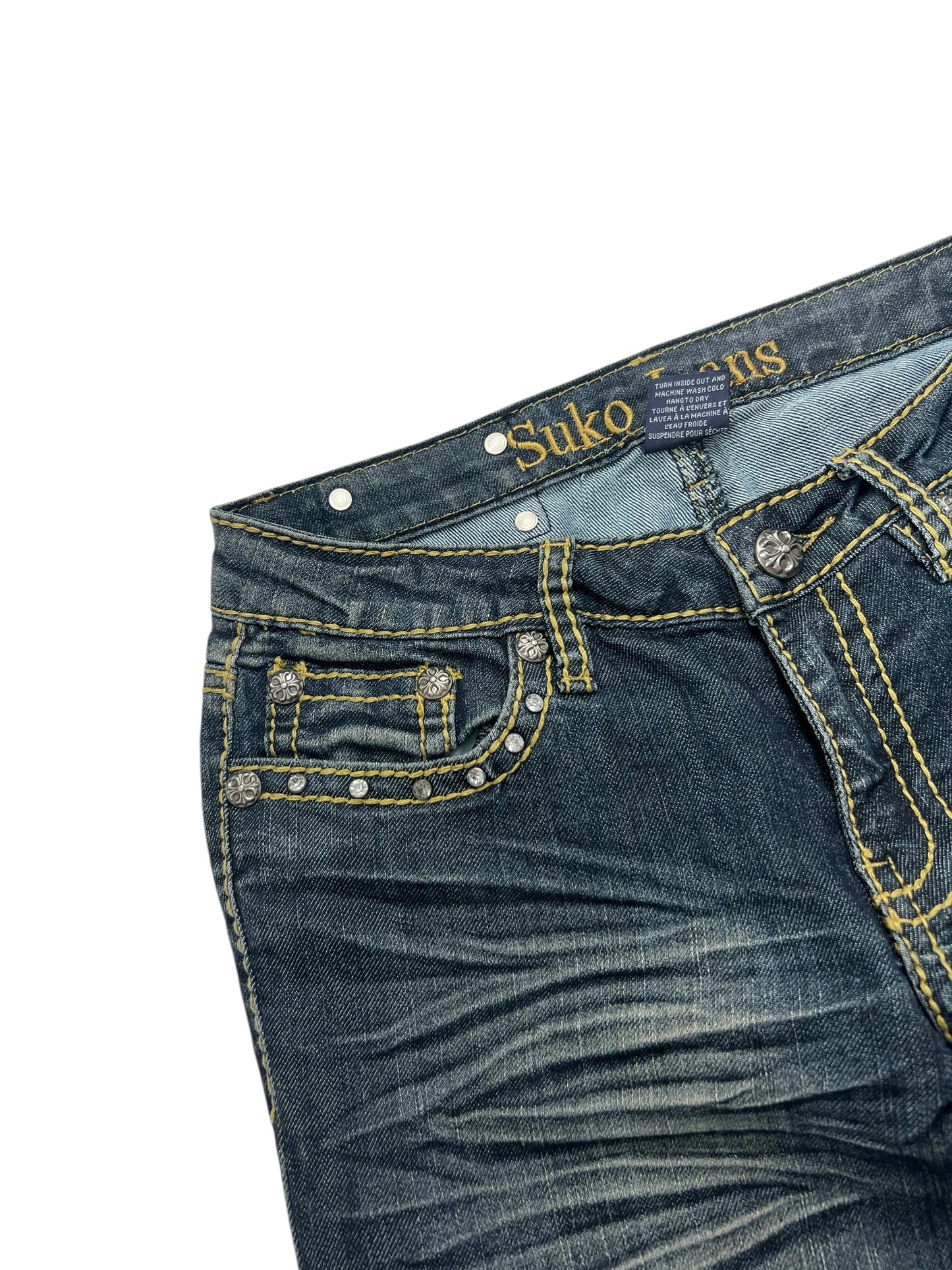 Nahaufnahme des oberen Teils des blauen Suko Jeans Mid Rise Boot (W26 x L34) von ZAZA Resell mit gelben Nähten, dekorativen Taschennieten, einem sichtbaren Markenetikett am Bund und einer klaren Sicht auf die Bundweite.
