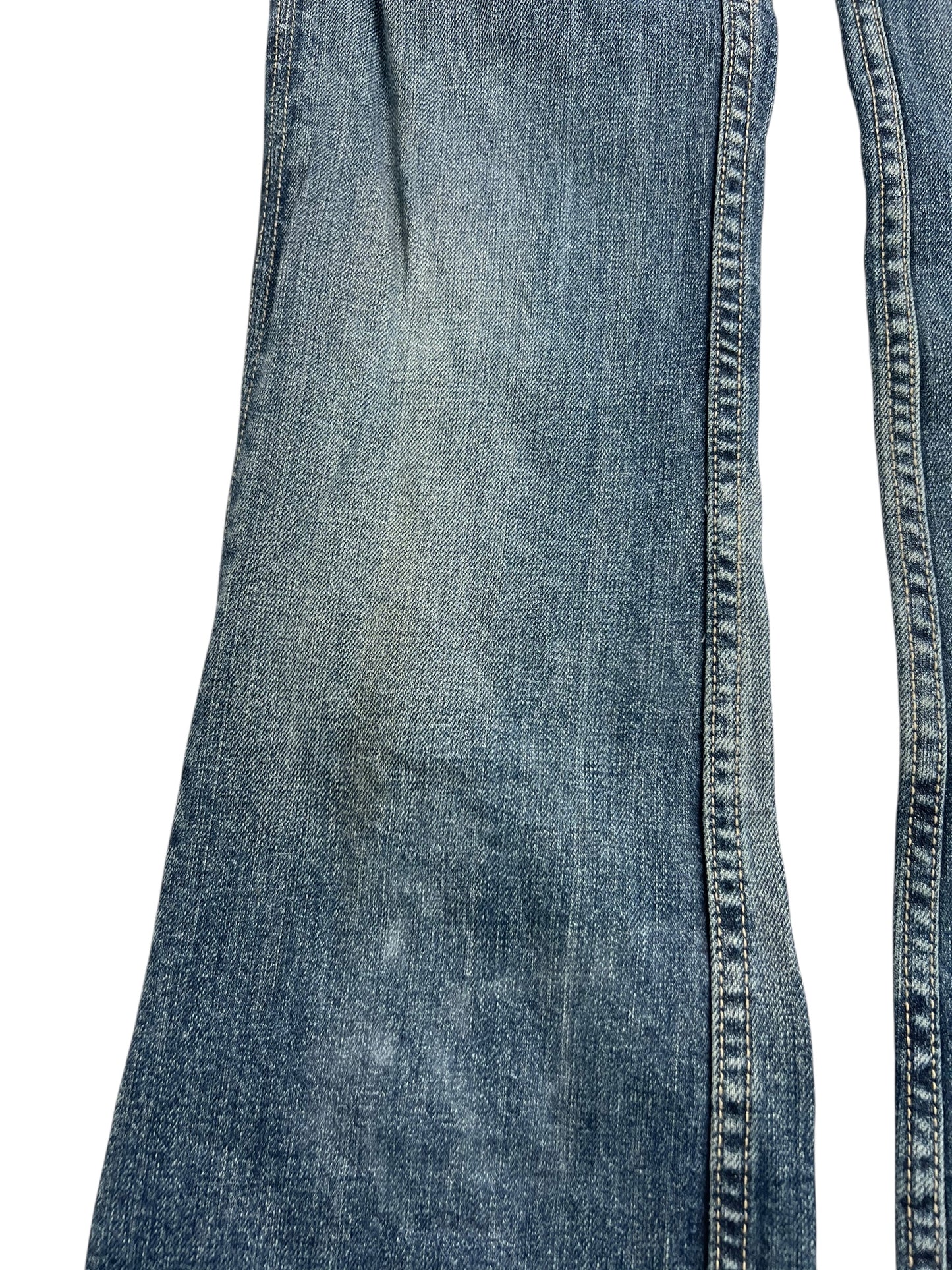 Nahaufnahme der Miss Me Low Rise Boot Jeans (W26 x L31) von ZAZA Resell, aus verblichenem blauem Denim mit abgenutzten Stellen am Knie und sichtbaren Nähten. Zustand: gebraucht.