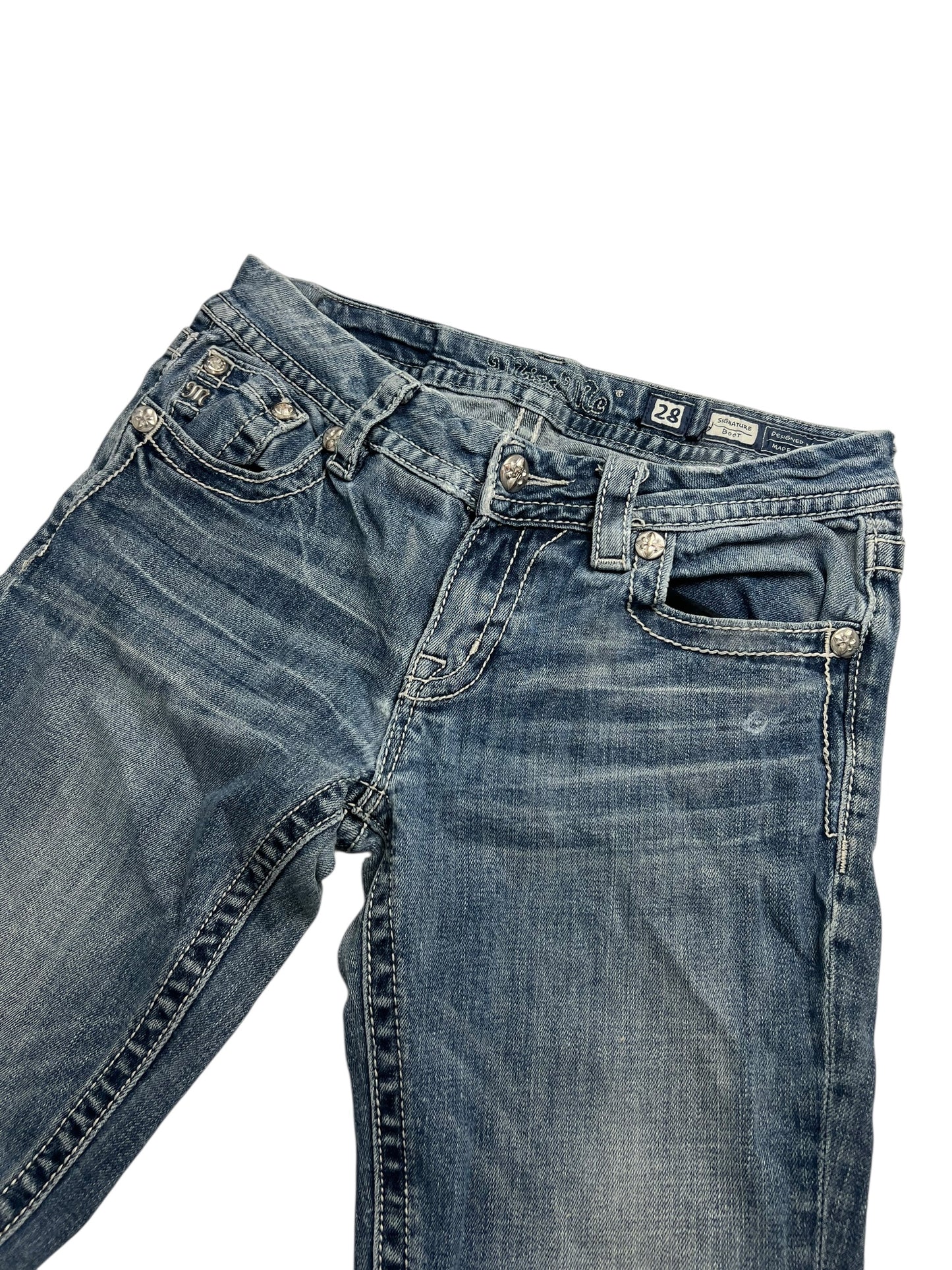 Die Miss Me Mid Rise Boot Jeans von ZAZA Resell (B28 x L26) besteht aus blauem Denim mit weißen Nähten, Fronttaschen, Gürtelschlaufen und einem Knopfverschluss. Sie hat einen leicht verblassten Look und liegt flach auf weißem Untergrund.
