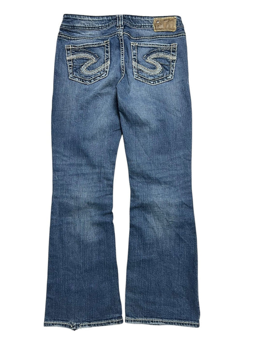 Ein Paar Silver Jeans Low Rise Boot | 29 (M) von ZAZA resell aus blauem Denim ist von hinten abgebildet und verfügt über zwei Gesäßtaschen mit weißer Stickerei, einen braunen Lederaufnäher am Bund und Labelgröße für eine perfekte Passform.
