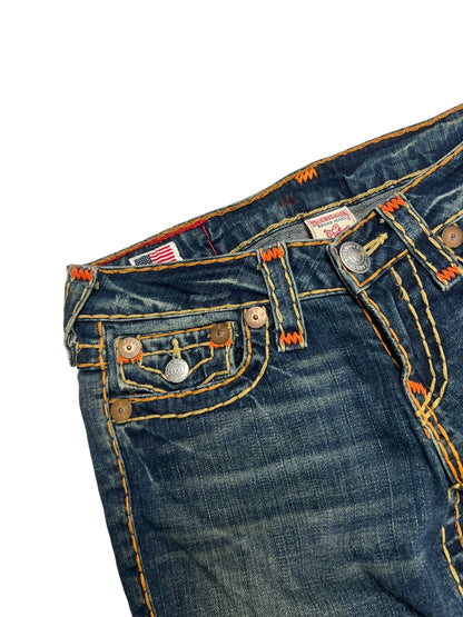 Eine Nahaufnahme von Bund und Tasche der True Religion Billy Super T - Low Rise Straight | 27 (M) Jeans von ZAZA resell, mit dunkelblauem Denim, orangefarbenen Nähten, Used-Details, Bundweite-Etikett, Metallknöpfen und einer amerikanischen Flagge auf weißem Hintergrund.