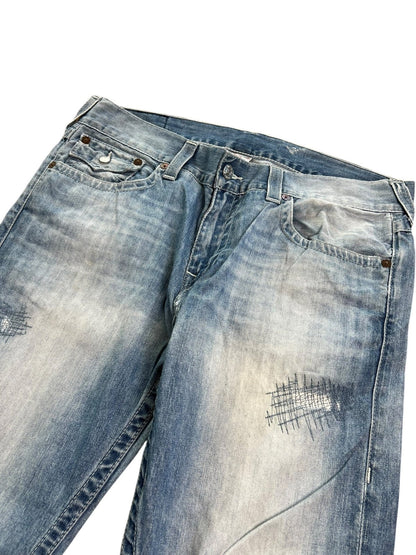 Die True Religion Straight Jeans von ZAZA resell in Größe 36 (XL) hat eine hellblaue Waschung, Distressed-Details, Patchwork-Nähte an den Oberschenkeln und eine Bundweite, die flach auf weißem Grund liegt.