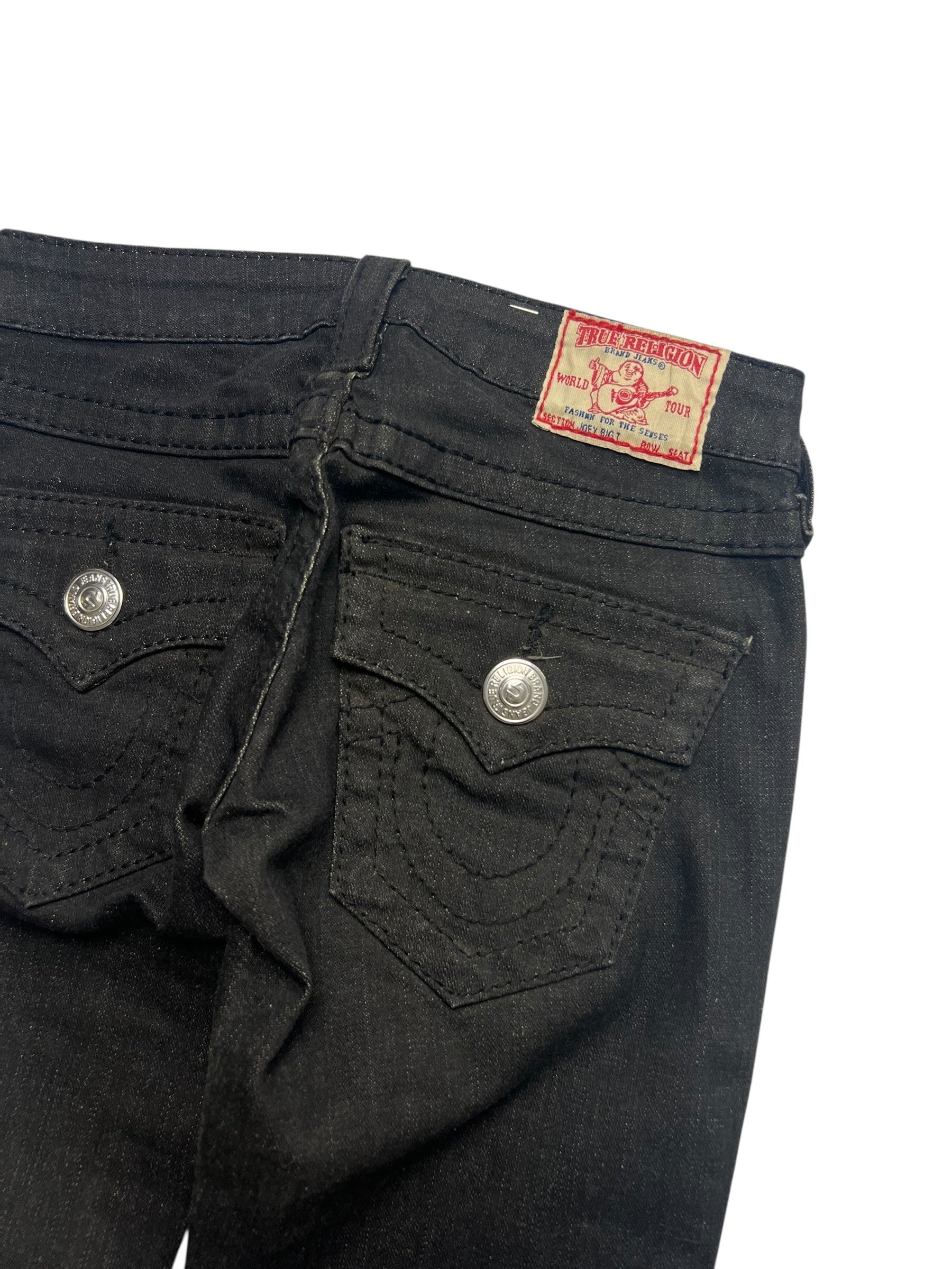 Die True Religion Joey - Low Rise Boot Jeans von ZAZA resell, Größe 24 (XXS), hat schwarzen Denim, silberne Knöpfe an der Gesäßtasche, ein rotes True Religion-Label am Bund und Details in Bundweite und Außenbeinlänge, abgebildet auf weißem Grund.