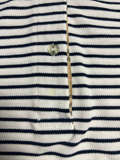 Nahaufnahme eines Burberry Polo Shirts | S von ZAZA resell, weiß mit schwarzen Querstreifen. Mit durchsichtigem Plastikknopf, aufgeknöpfter Knopfleiste, sichtbaren Nähten und beigem Innenfutter. Zustand 8/10. Maße in Zentimetern auf Anfrage.