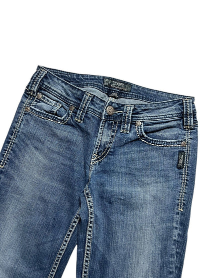 Die Silver Jeans Low Rise Boot in Größe 29 (M) von ZAZA resell hat blauen Denim, weiße Kontrastnähte, Taschen vorne, Gürtelschlaufen und einen Metallknopfverschluss. Bundweite und Labelgröße sorgen für die perfekte Passform. Abgebildet auf weißem Hintergrund.