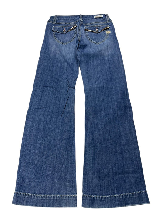 Eine Jeans „Miss Me Low Rise Flare“ von ZAZA Resell (B28 x L30), blauer Denim mit weitem Bein, flach gelegt und von hinten betrachtet, mit zwei Gesäßtaschen mit Knopfklappen und einem goldenen Kettendetail – extrem selten, sehr guter Zustand.