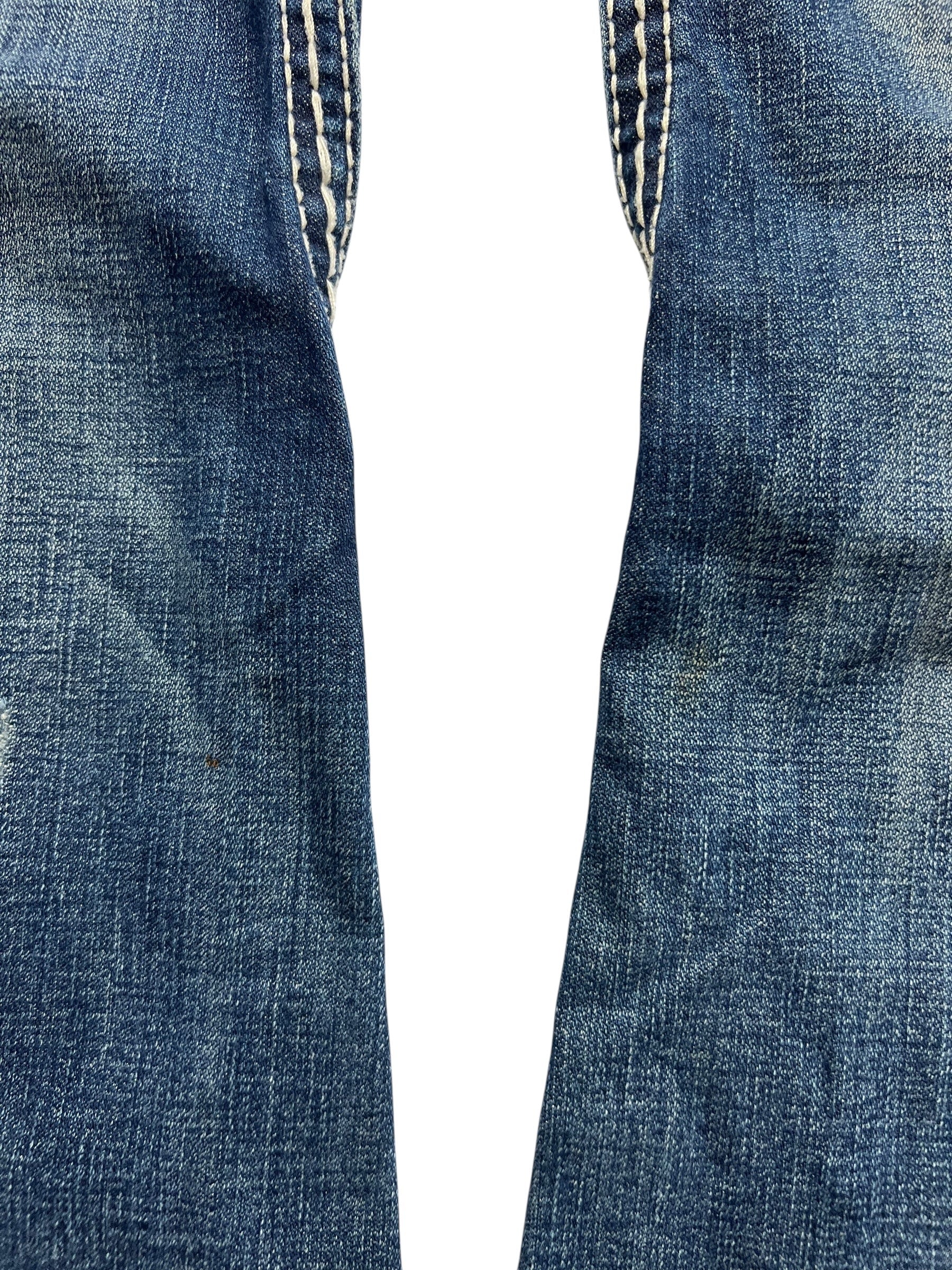 Nahaufnahme der True Religion Joey Big T - Low Rise Boot Jeans, Größe 28 (Bundweite 40), von ZAZA resell, zeigt blauen Denim mit sichtbaren Nähten und verblassten Innenseiten der Oberschenkel vor einem weißen Hintergrund.