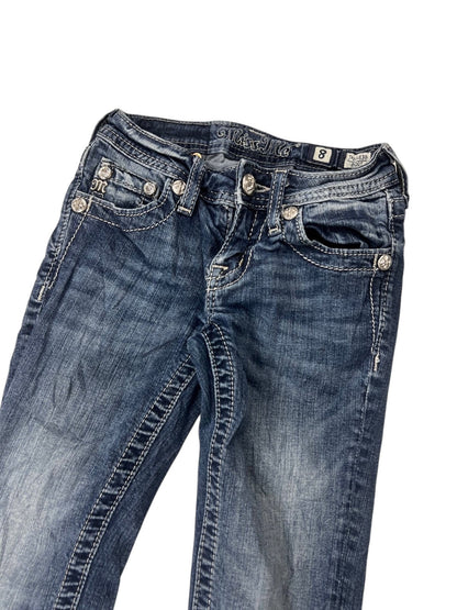 Ein Paar Miss Me Boot Jeans von ZAZA resell in Blau mit weißen Nähten und silbernen Zierknöpfen. Ausgestellt auf weißem Grund, mit einer Labelgröße 8 am Bund und einer Bundweite von 27,5 cm. Größe: XXXS (Kindergröße).
