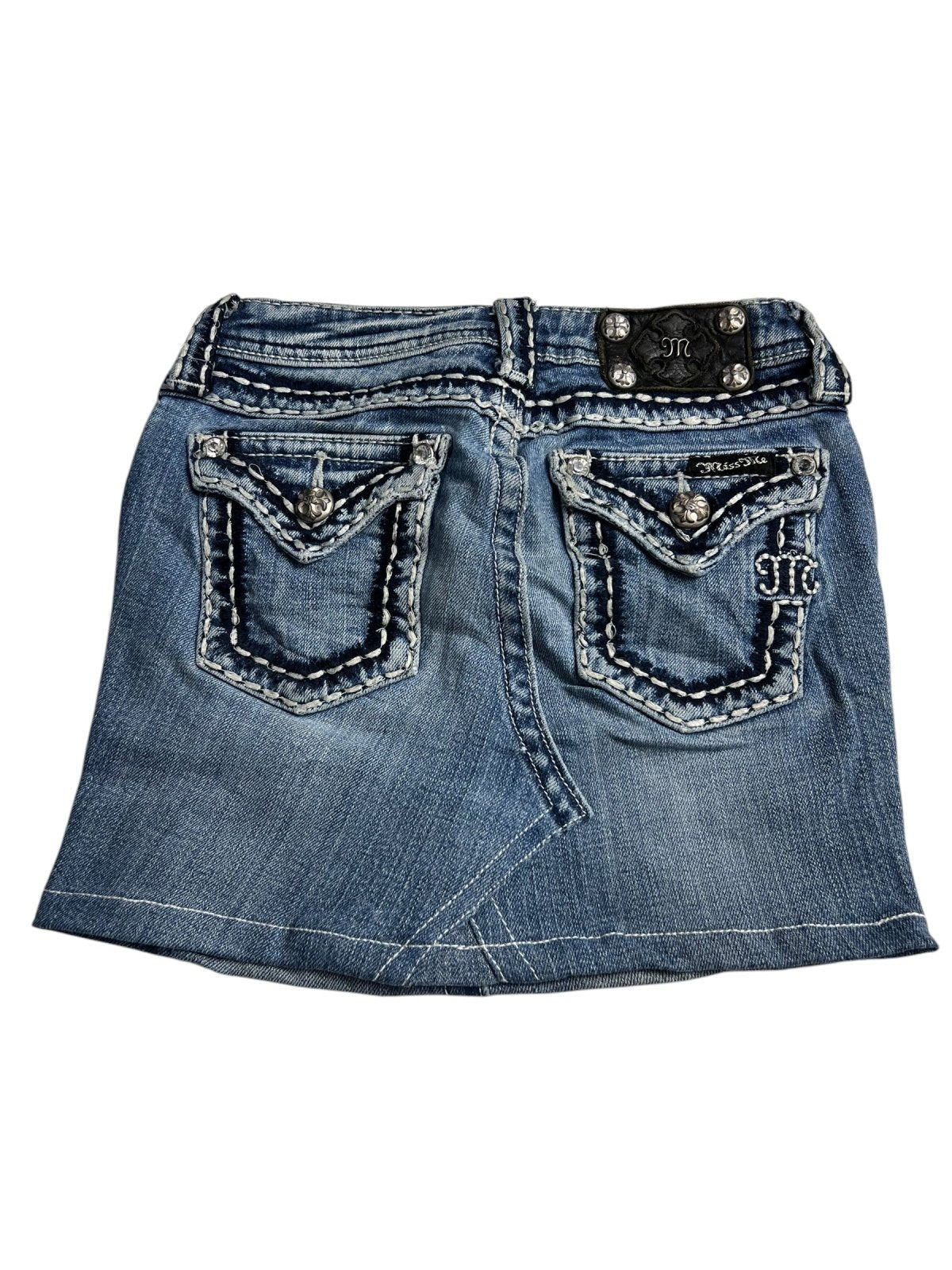 Der Miss Me Skirt | XXS von ZAZA resell ist ein blauer Kinderrock aus Denim mit weißen und dekorativen Nähten, zwei Pattentaschen hinten mit silberfarbenen Knöpfen und einem schwarzen Bundlabel. Maßangaben helfen, die perfekte Passform für Ihr Kind zu gewährleisten.