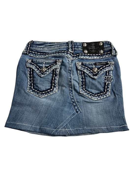 Der Miss Me Skirt | XXS von ZAZA resell ist ein blauer Kinderrock aus Denim mit weißen und dekorativen Nähten, zwei Pattentaschen hinten mit silberfarbenen Knöpfen und einem schwarzen Bundlabel. Maßangaben helfen, die perfekte Passform für Ihr Kind zu gewährleisten.