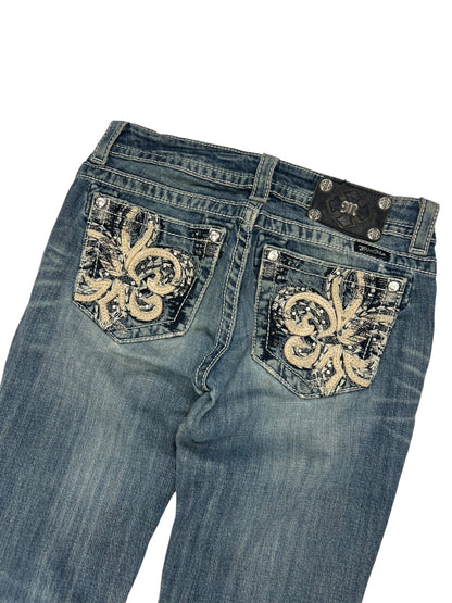 Die Miss Me Low Rise Straight Jeans (Größe 27/S) von ZAZA resell ist mit dekorativen Fleur-de-Lis-Stickereien auf den Gesäßtaschen und einem schwarzen Markenpatch über der rechten Tasche versehen.
