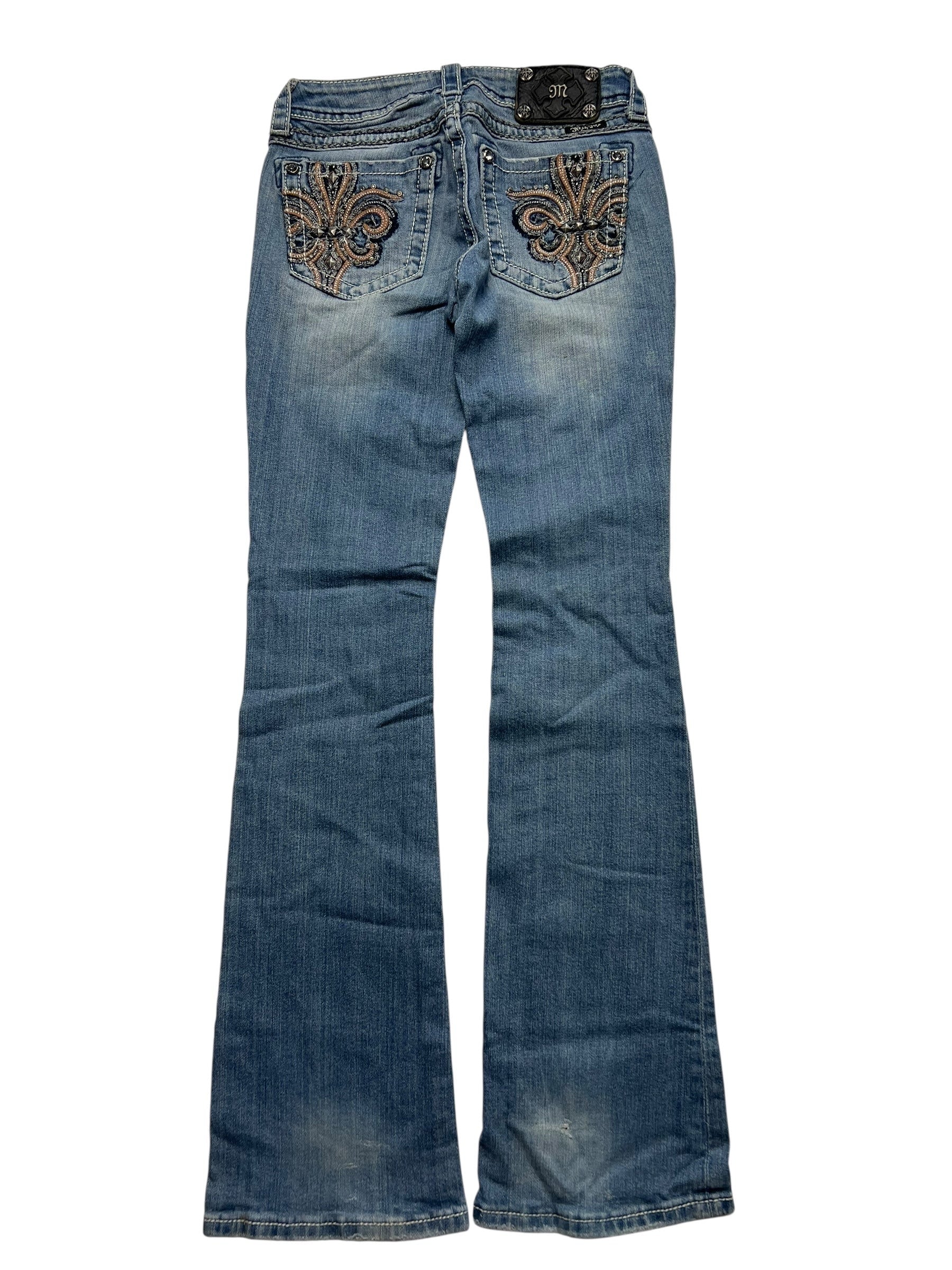Ein Paar Miss Me Low Rise Boot Jeans von ZAZA resell in Größe 26 (S)ki, blauer Bootcut-Stil mit dekorativer Stickerei auf den Gesäßtaschen, flach auf weißem Hintergrund für eine ideale Passform dargestellt.