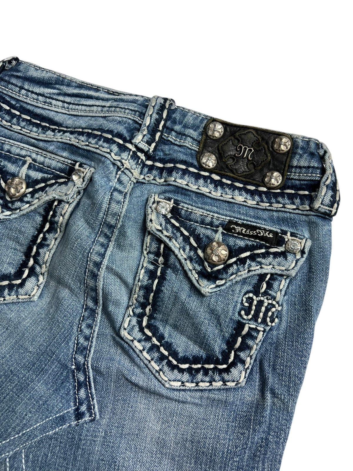 Nahaufnahme der Rückseite eines blauen Miss Me Rocks (XXS) aus dem ZAZA-Wiederverkauf mit detaillierten Nähten, verzierten Taschen mit Metallknöpfen und einem schwarzen Strass-Etikett - perfekt zum Kombinieren mit Ihrem Lieblingsrock.