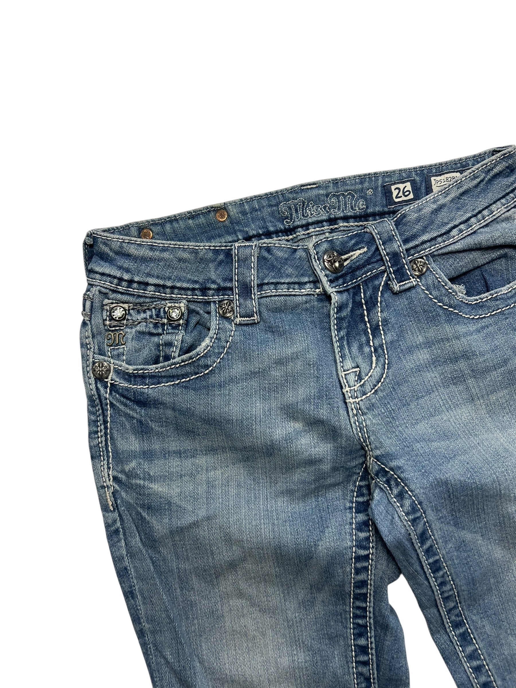Ein Paar Miss Me Low Rise Boot Jeans in Größe 26 (S) von ZAZA resell mit blauem Denim, weißen Nähten und dekorativen Taschen auf der Vorderseite, abgebildet auf weißem Hintergrund.